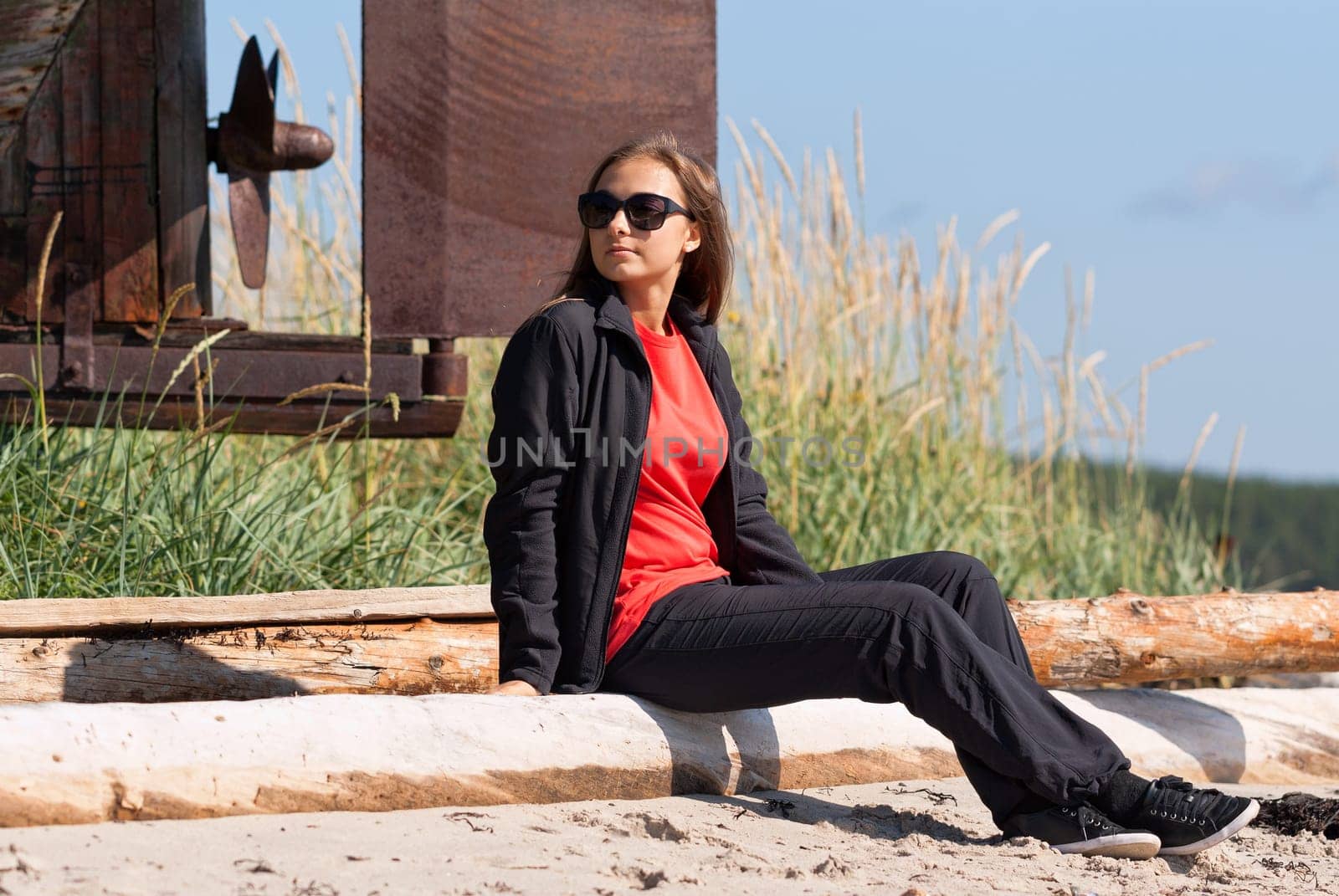 Girl on a deserted beach in the background of an old rusty screws fishing schooner