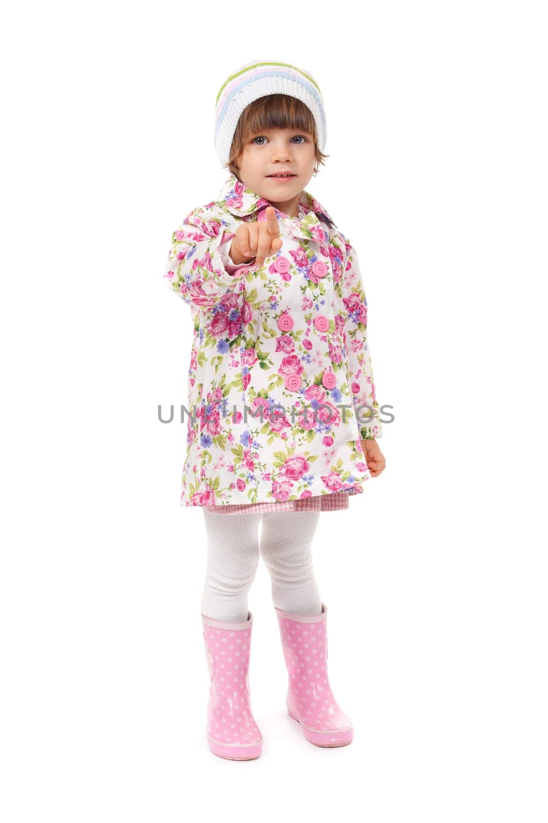 little girl in boots and a jacket shows finger. Isolate on white