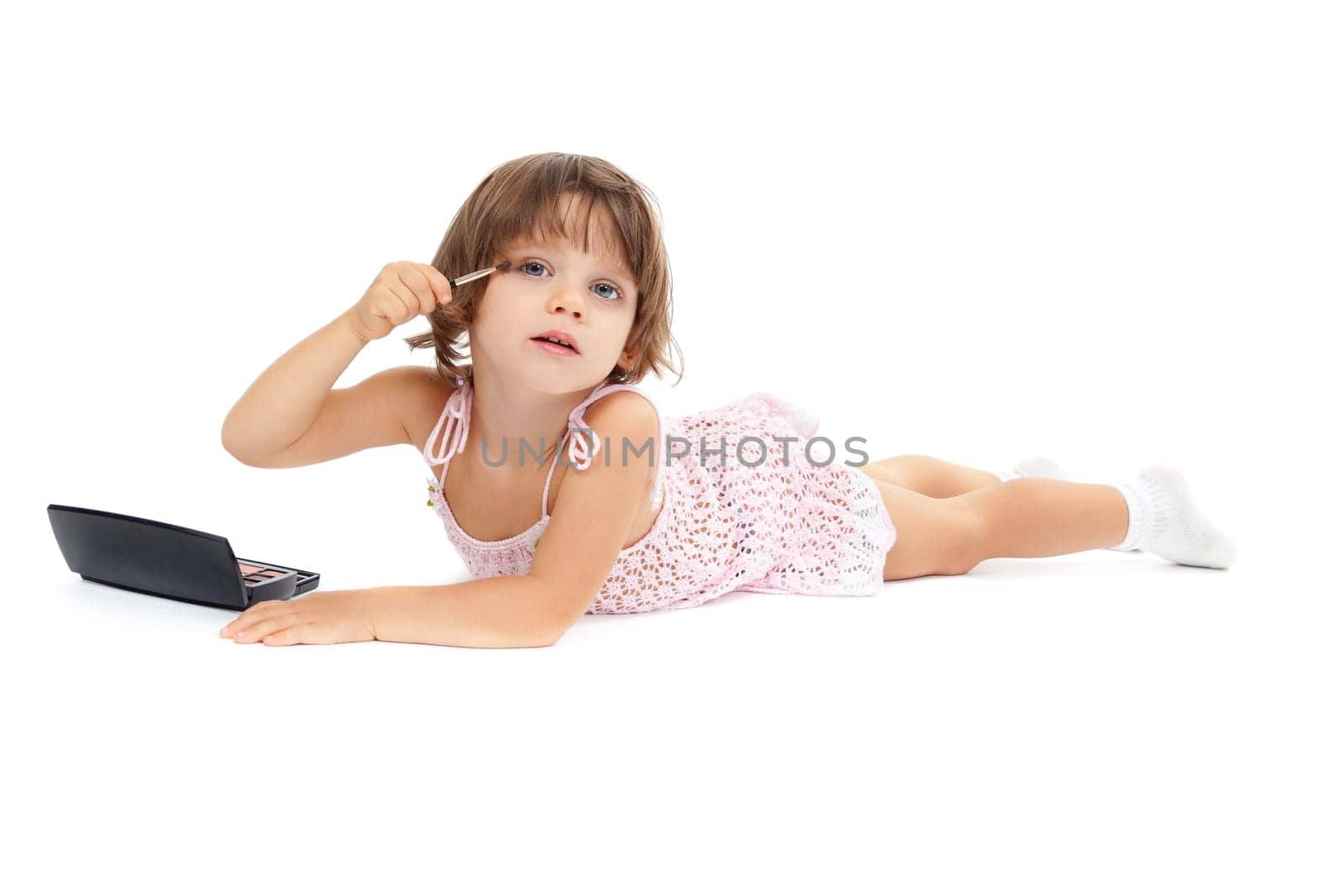 beautiful little girl paints the eyelashes mascara. Isolated on white background