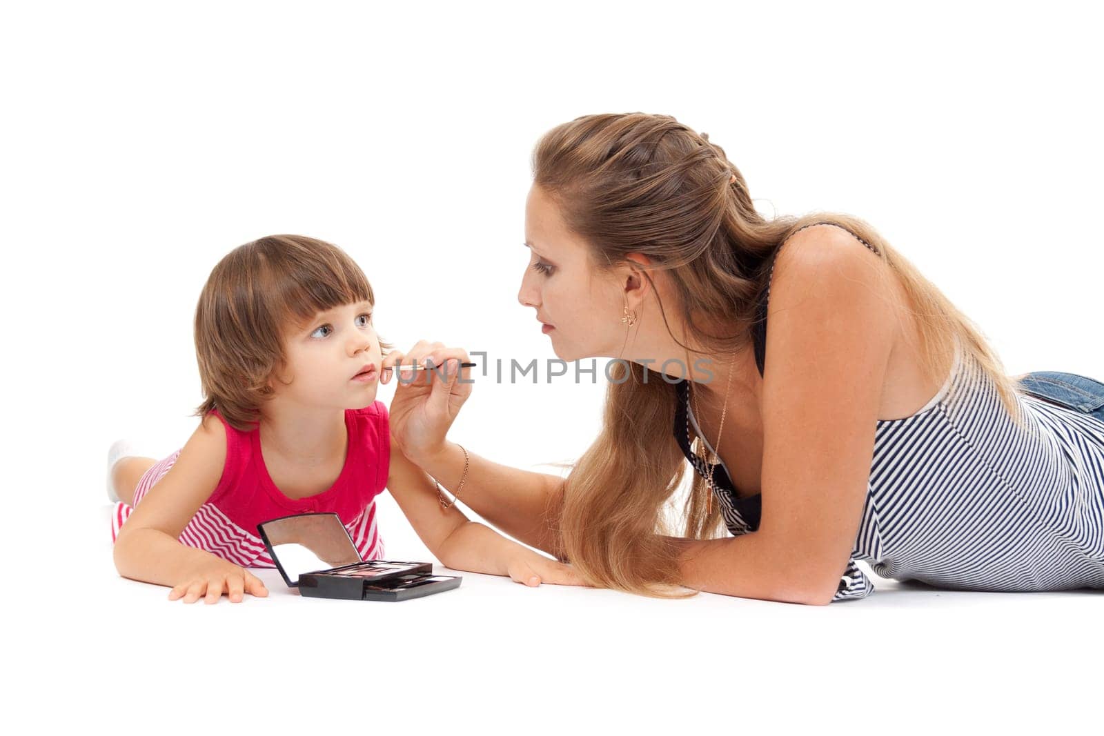 Young mother paints lipstick little daughter in the studio on a white background