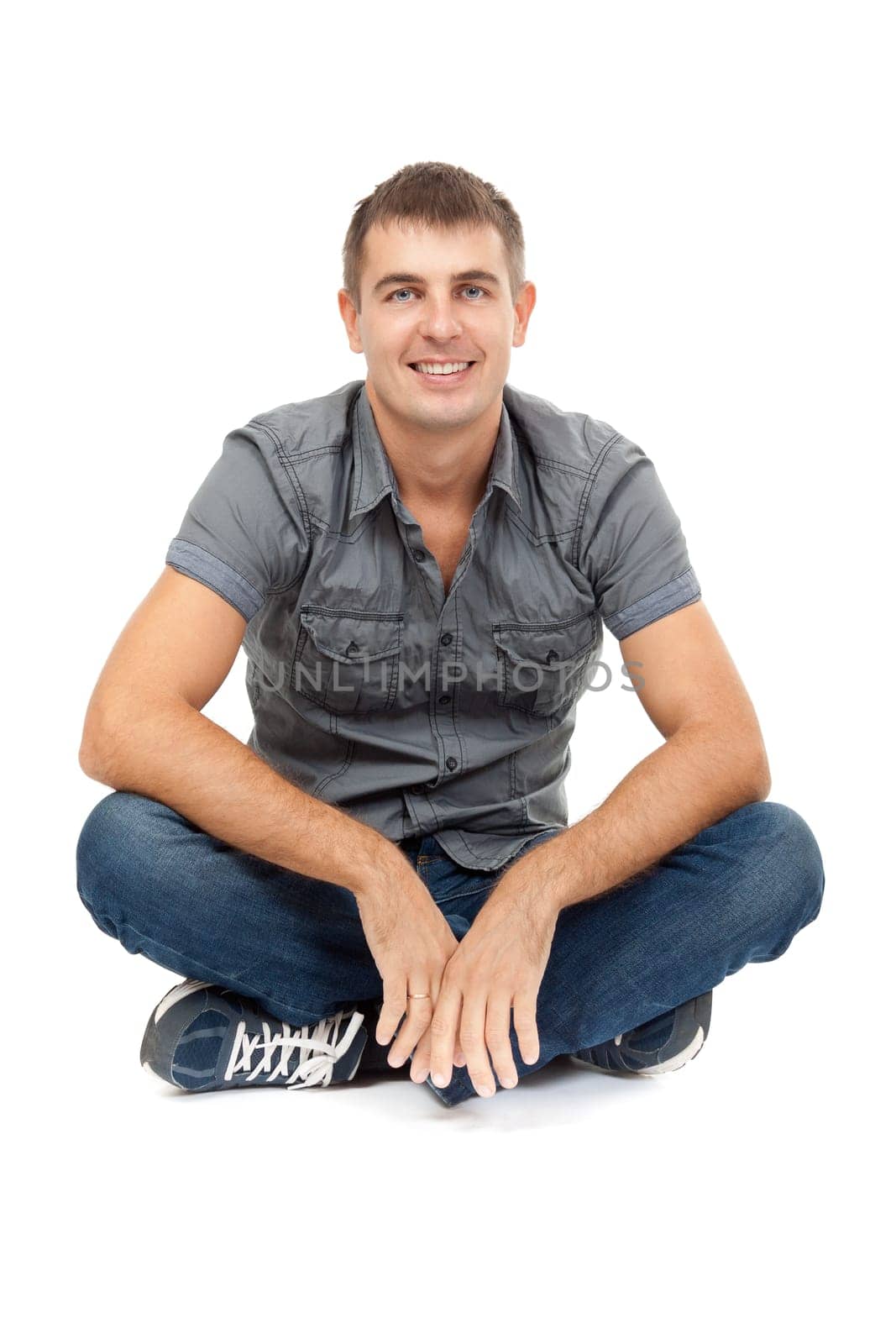 casual man sitting in lotus position, smiling. Studio portrait on white background.
