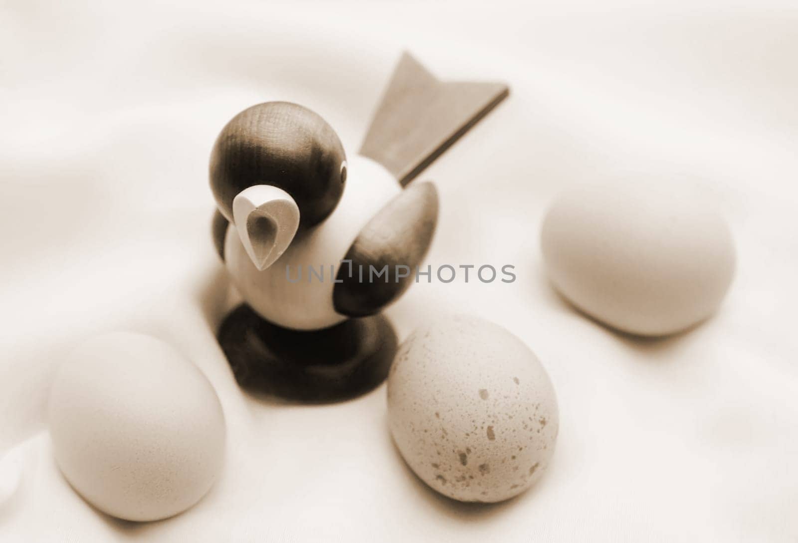 The photograph of three chicken eggs on a cloth with a wooden figure (Piepmatz).