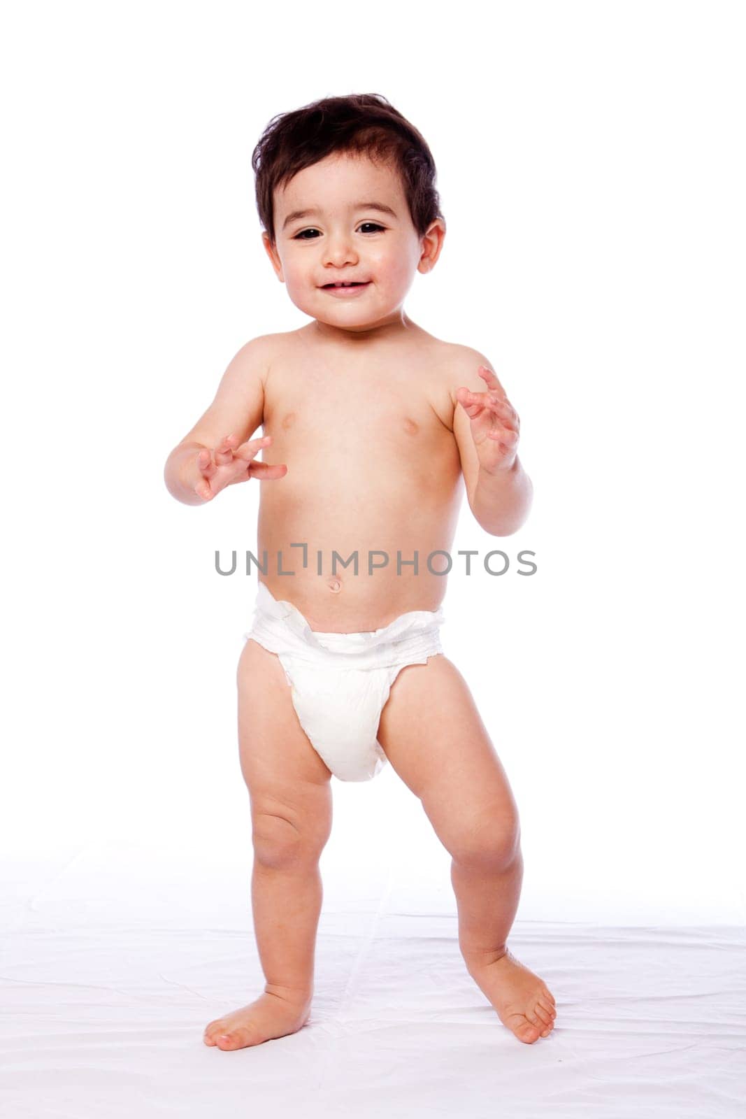 Cute happy baby toddler first steps learning how to walk in diaper, childhood concept.