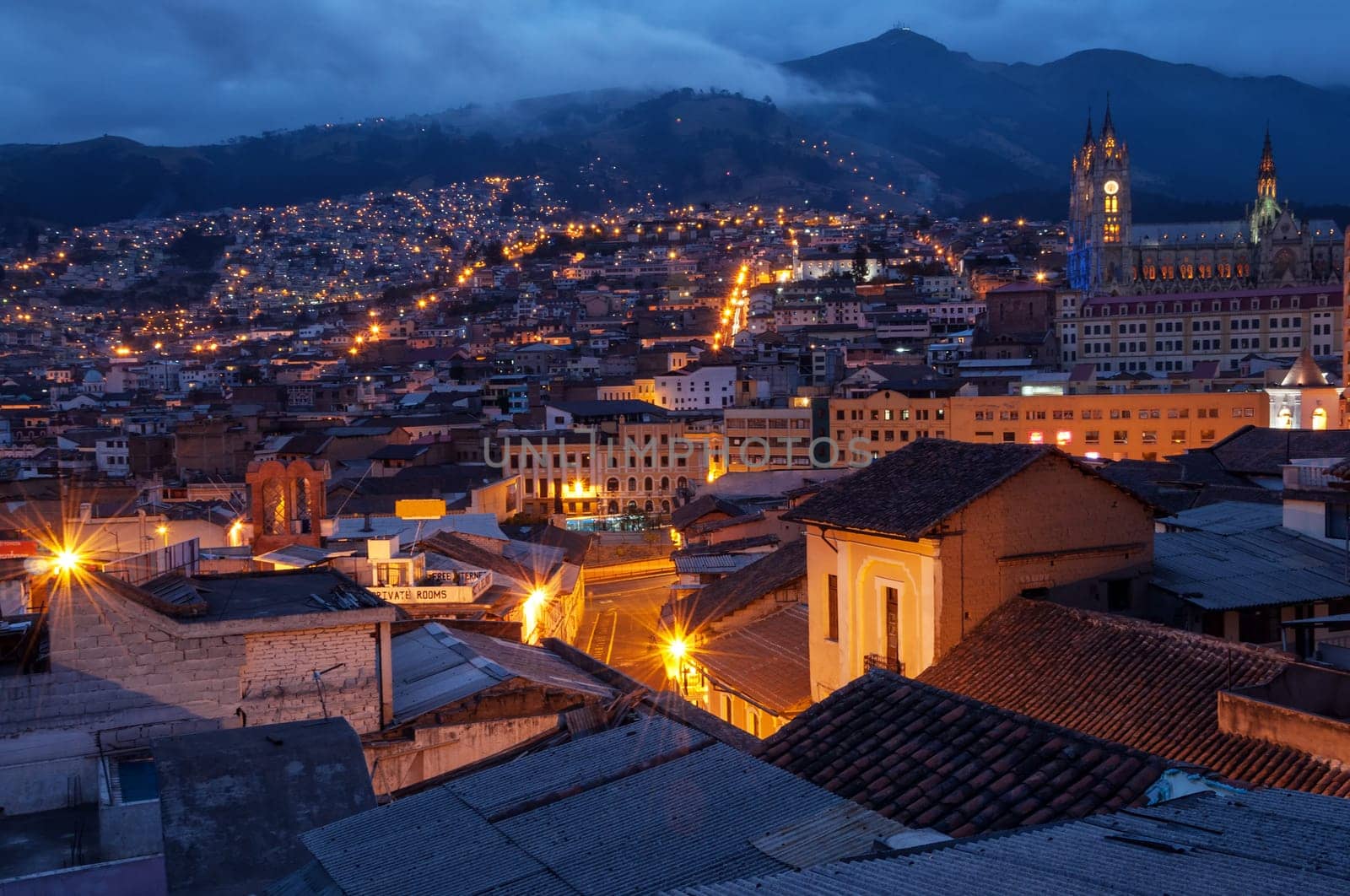 Quito, Ecuador old town and basilica at night with mountains in the background