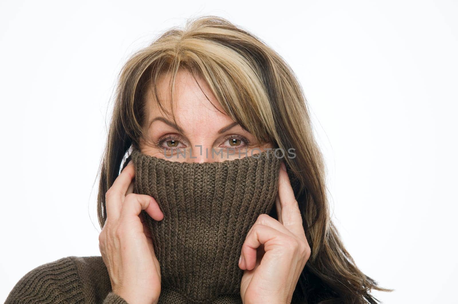 Head and shoulders shot of a middle-aged woman with a turtleneck half pulled over her face looking head-on at the camera