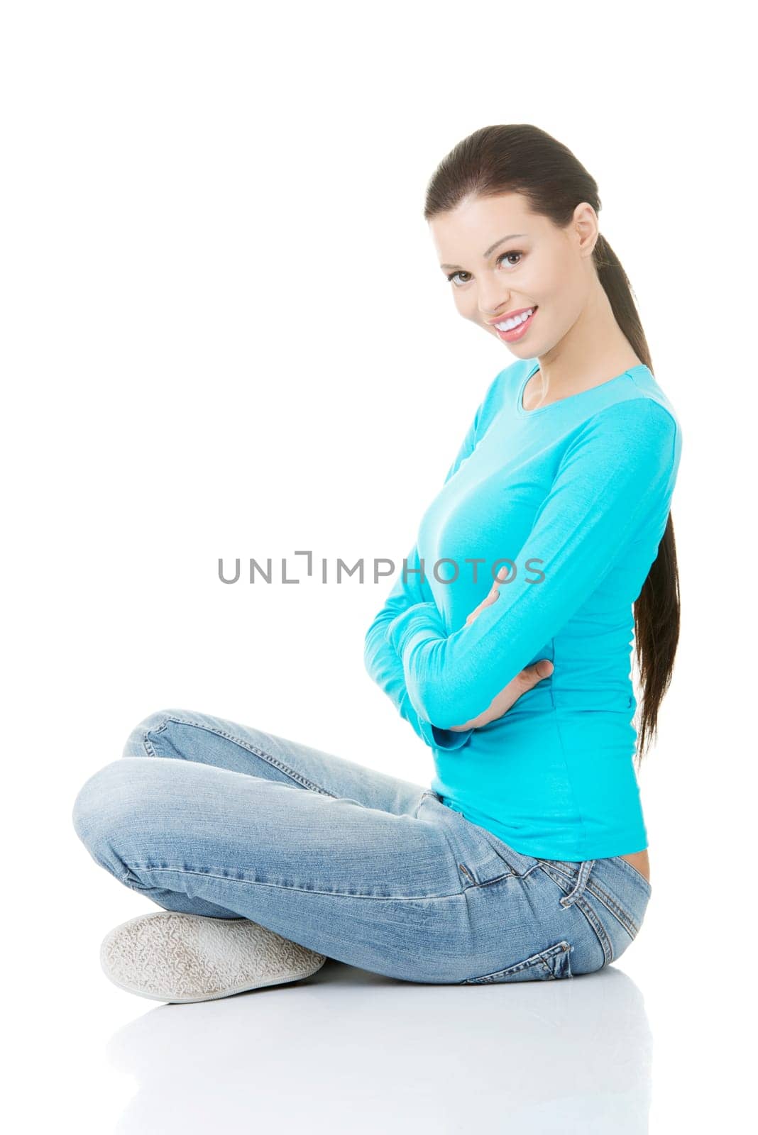 Young beautiful woman in casual clothes sitting on floor, isolated on white