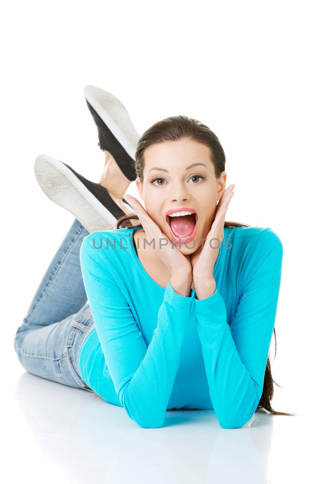 Young beautiful happy woman in casual clothes lying on floor, isolated on white