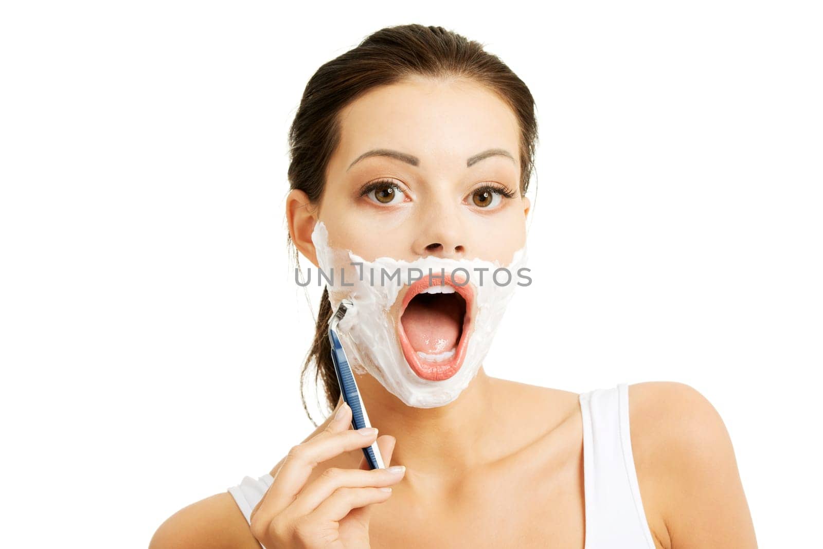 Beautiful young woman shaving her face with a razor