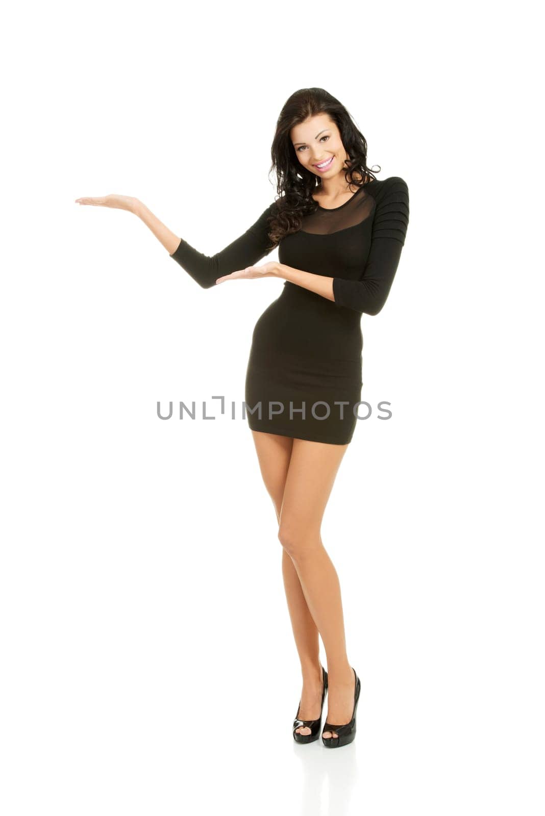 Young beautiful caucasian brunette in gorgeous sexy dress showing copy space on her palm.