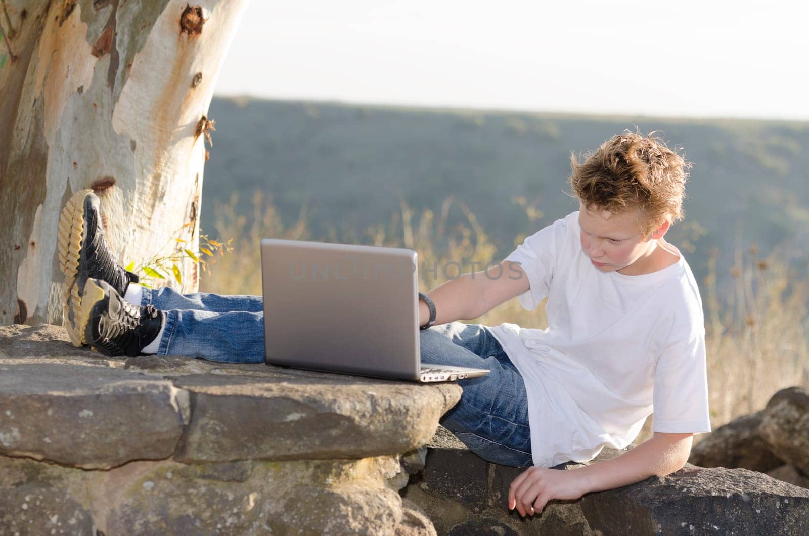 Guy relax on nature and works on a laptop