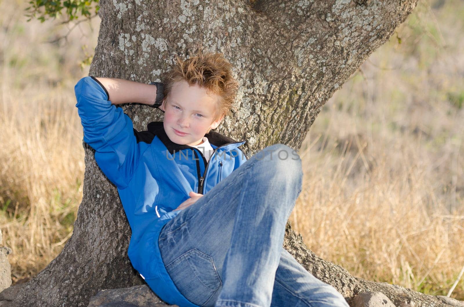 Teenager in sportswears sits under tree on nature