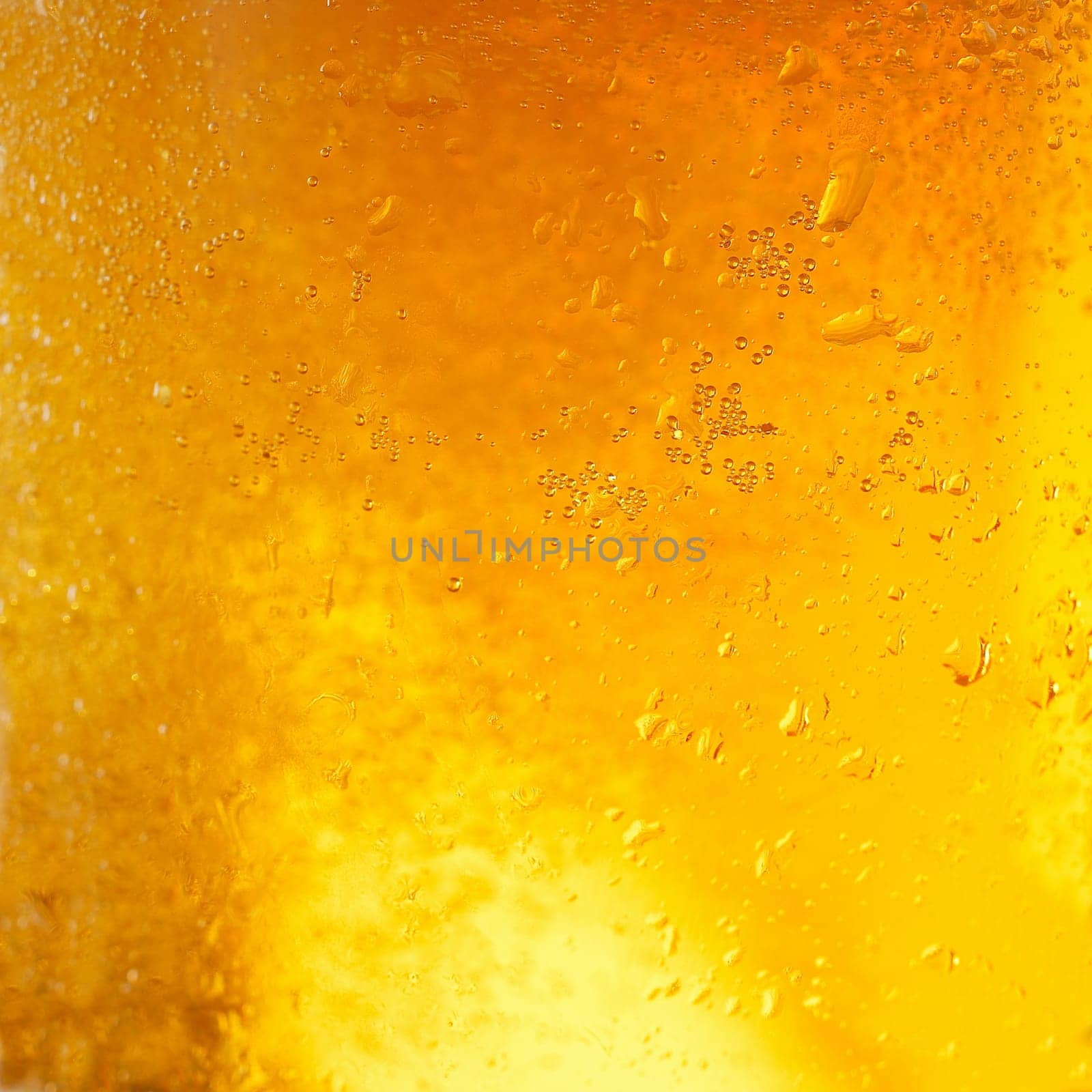 A background created from a closeup of cold light beer in a glass, with condensation droplets on the outside of the glass