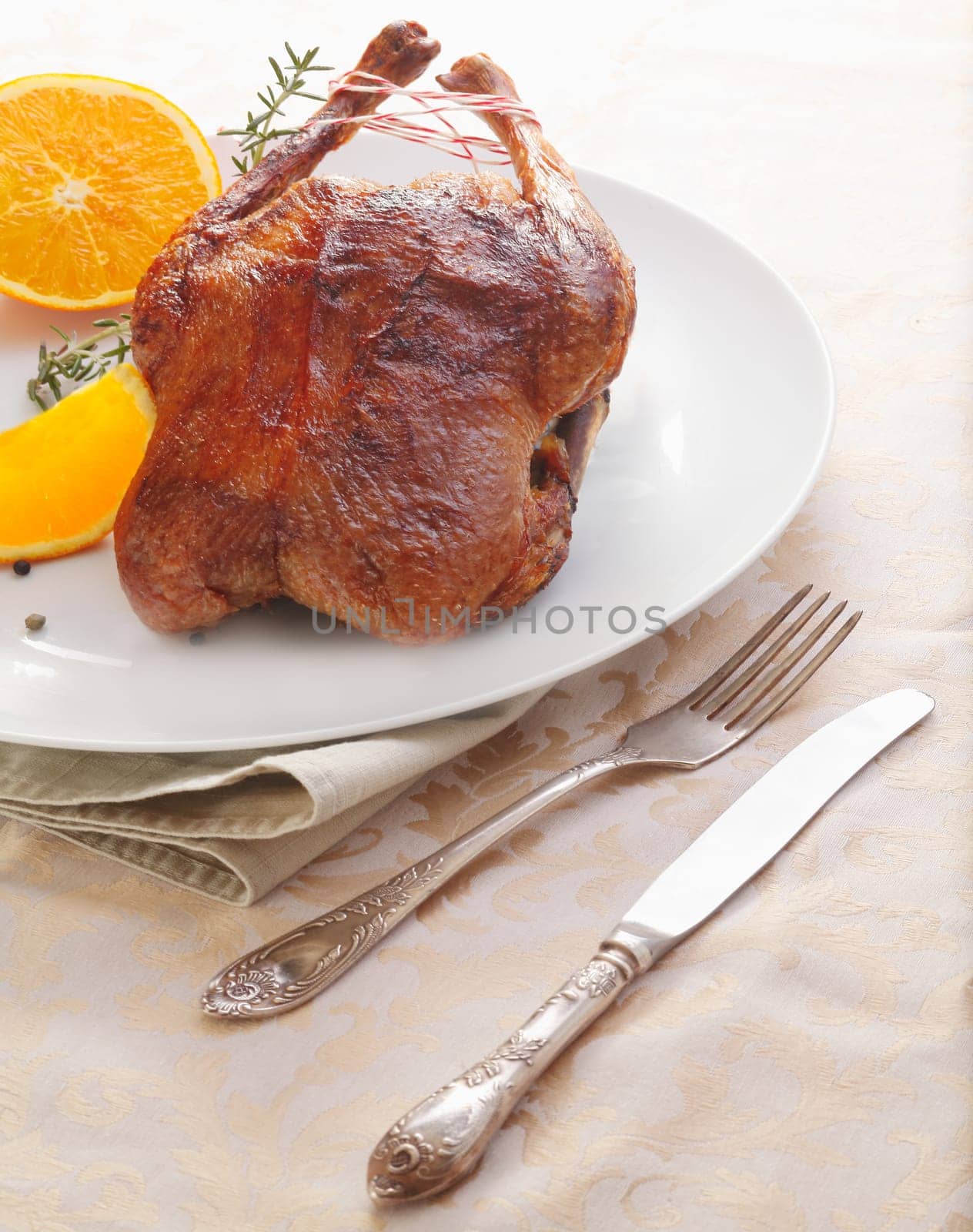 Delicious whole roasted chicken or duck served whole with sliced fresh oranges and a sprig of rosemary