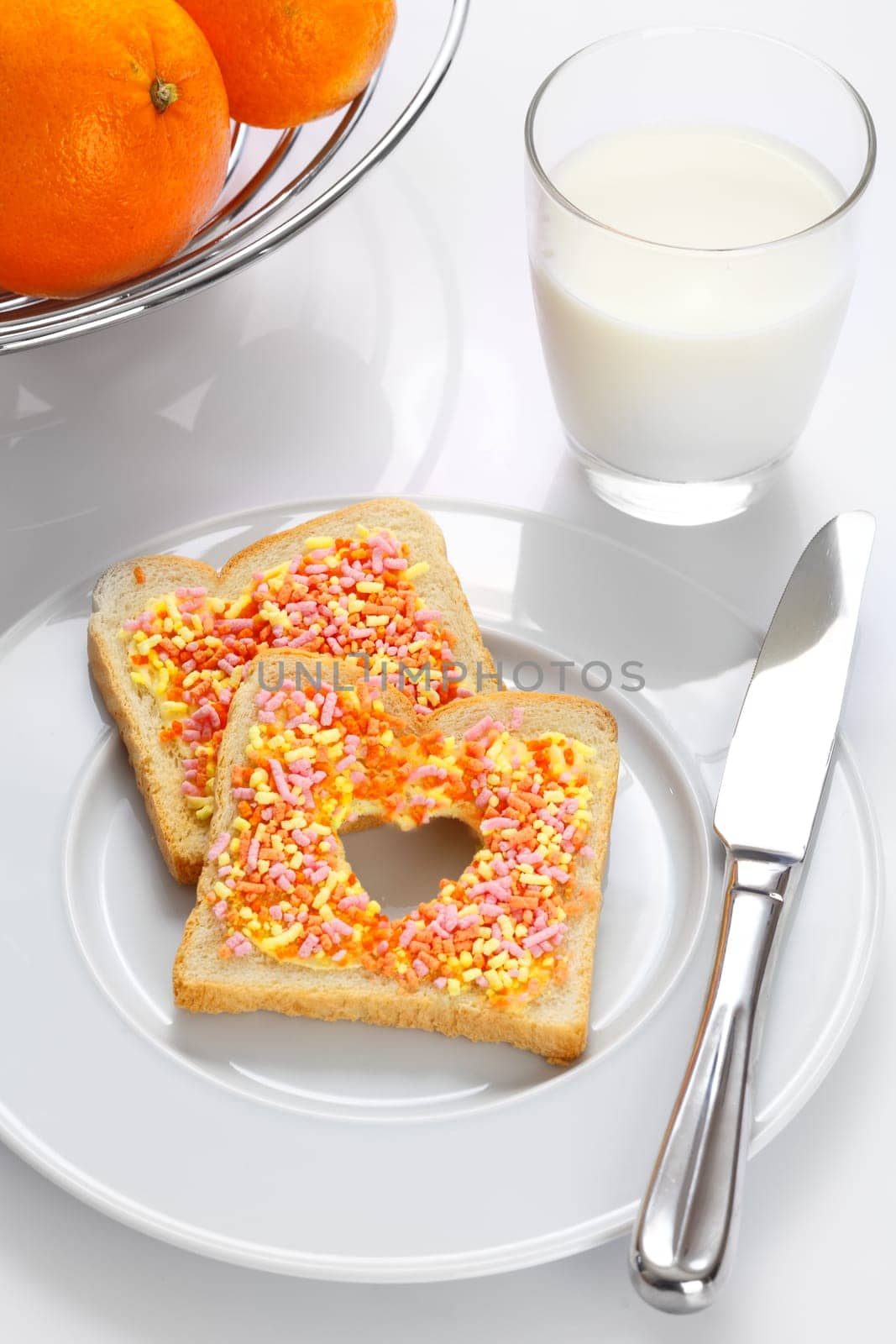 Tasty elegant breakfast made of slices of bread with candies, oranges and milk