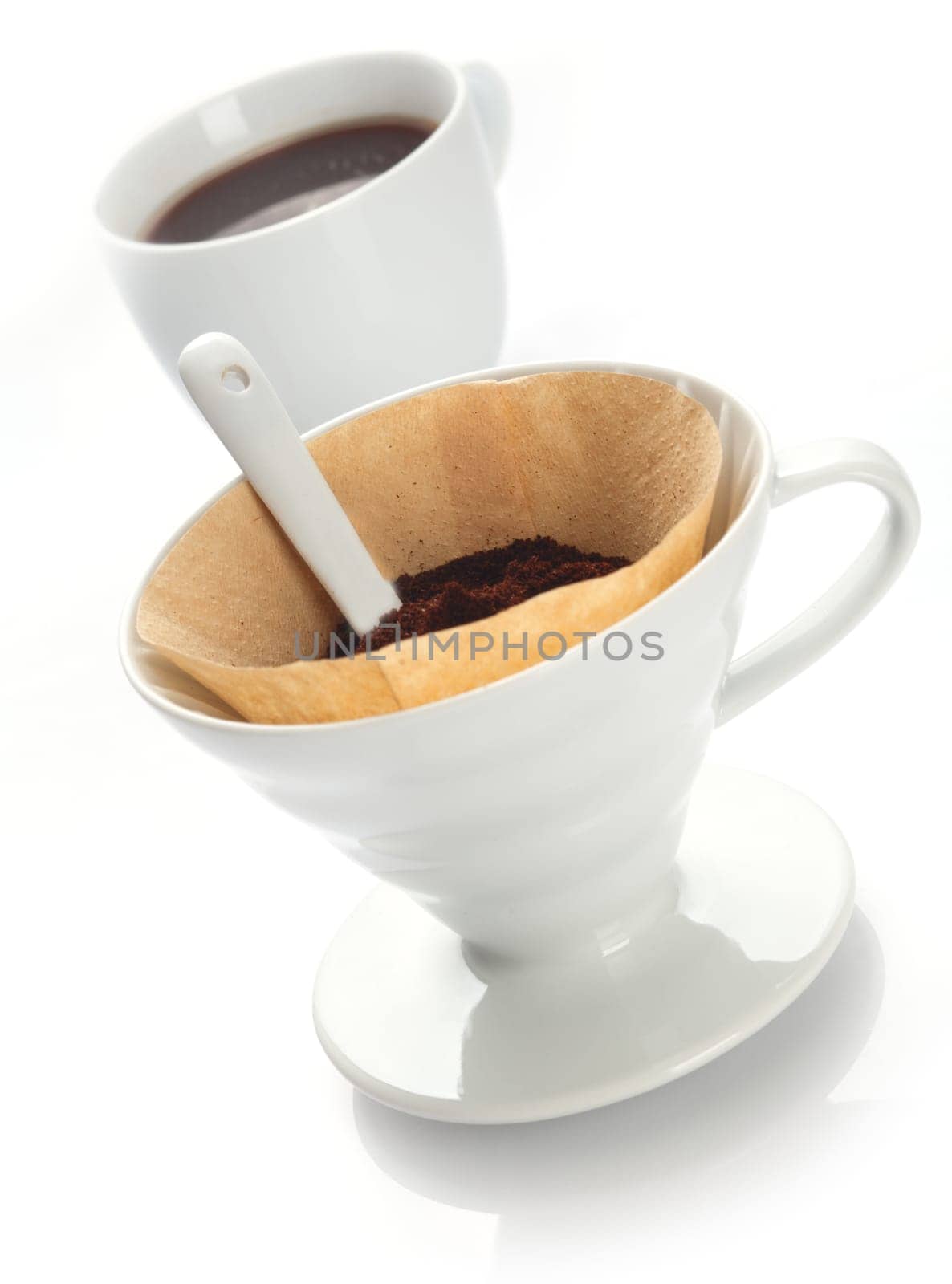 Portable plain white china filter funnel with filter paper filled with freshly ground coffee beans for preparing a fresh brew in a single cup