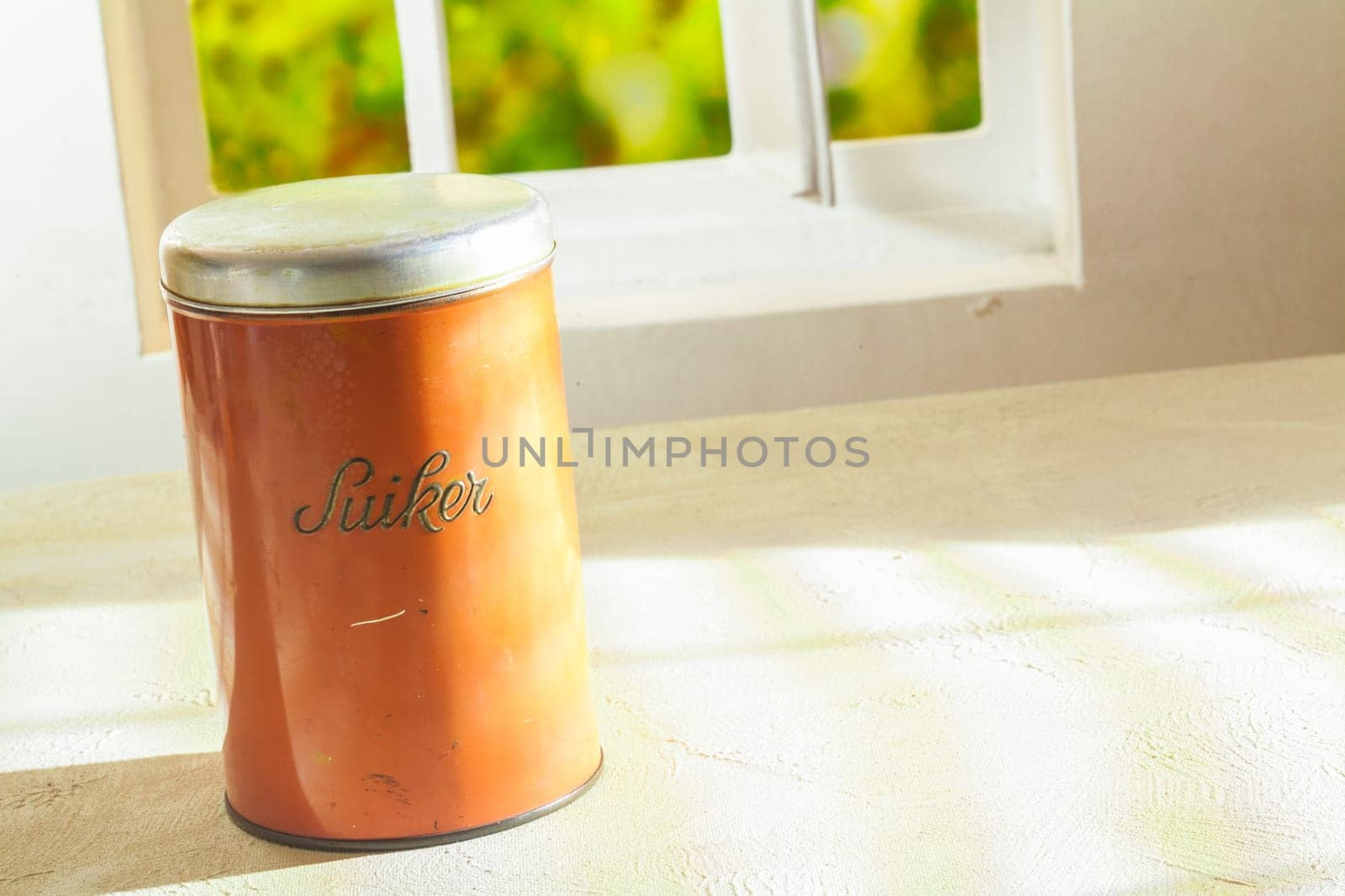 Tin labelled sugar, or suiker, standing on a table top with copyspace