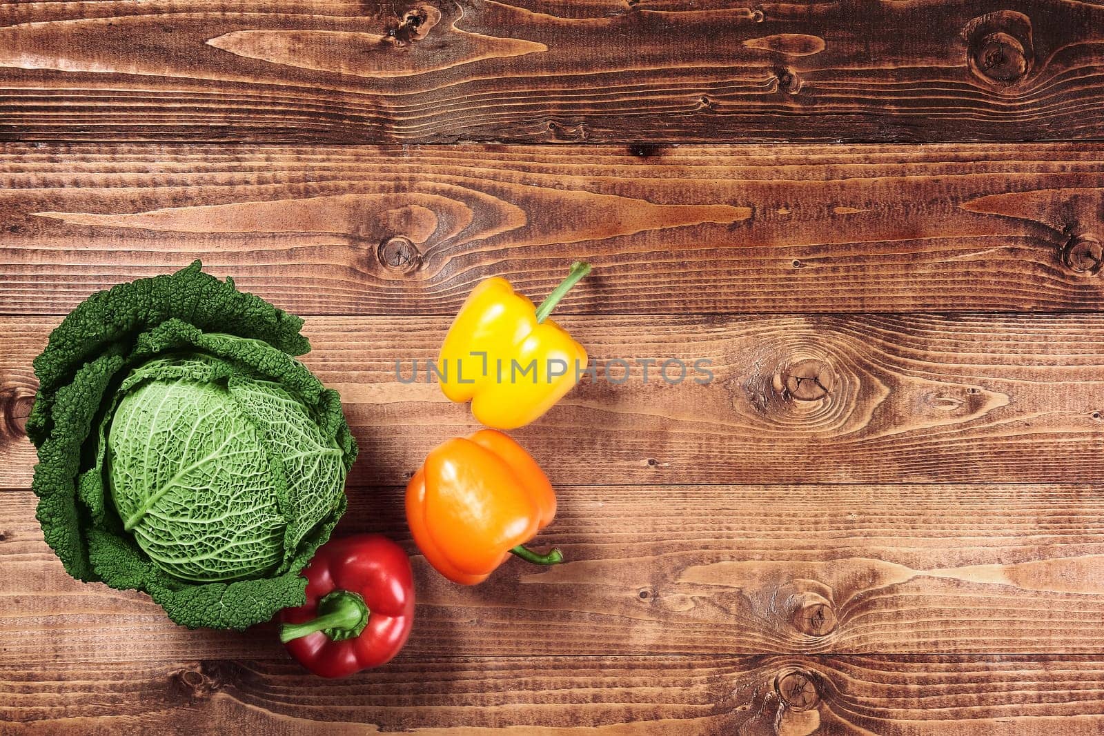 Cabbage and red and yellow peppers on wood