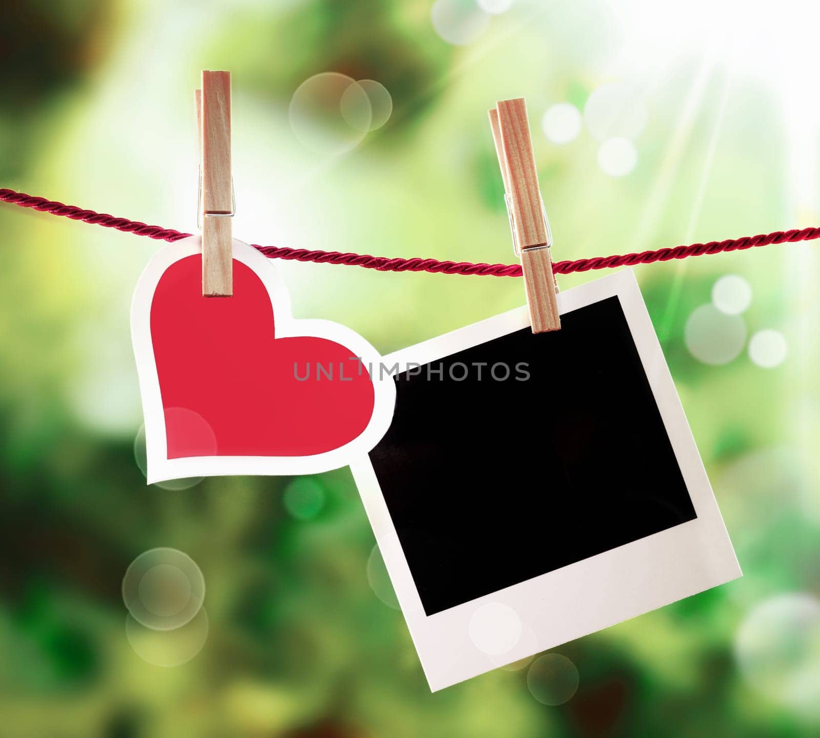Romantic Valentine or anniversary card with a fresh red heart hanging on a line outdoors alongside an empty instant photo frame bathed in ethereal golden sunlight for those special memories