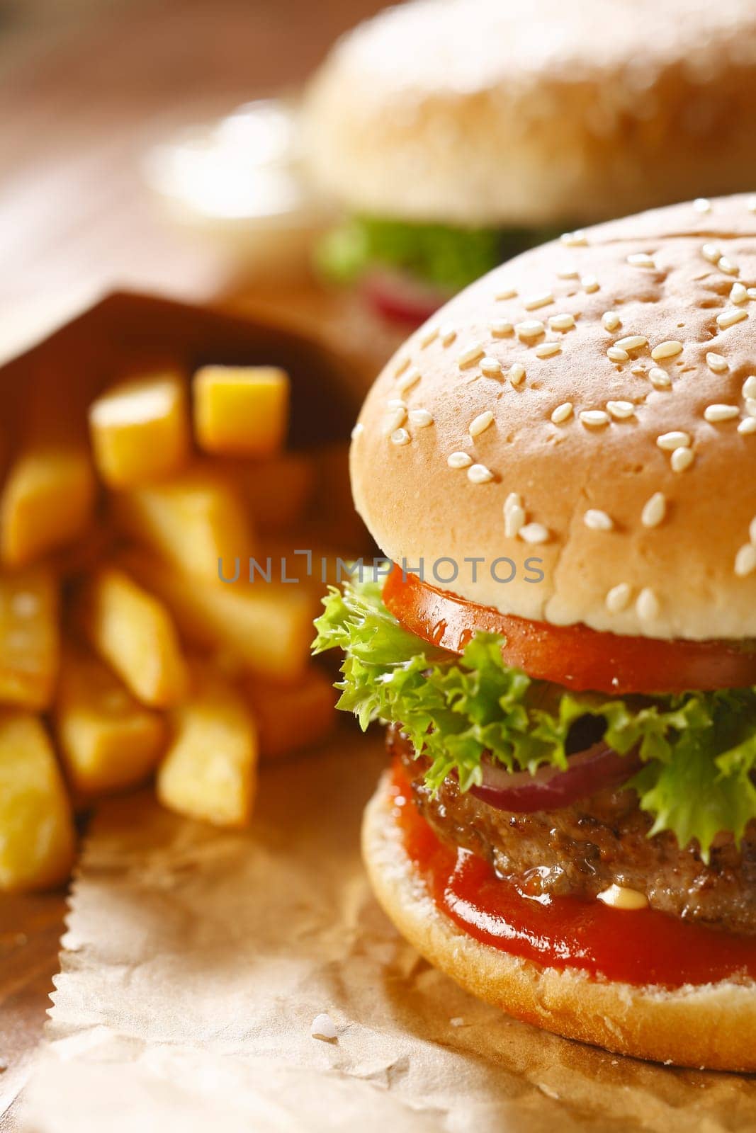 Two hamburgers and french fries with sesame bun on brown paper. selective focus