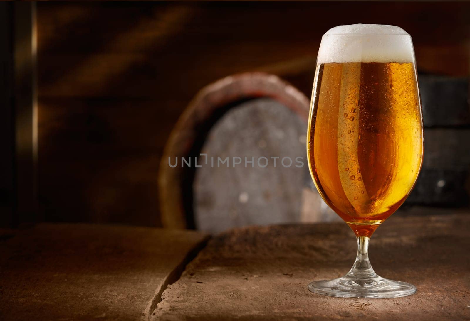 Closeup of a glass of fresh foamy beer on a table in a vintage beer cellar