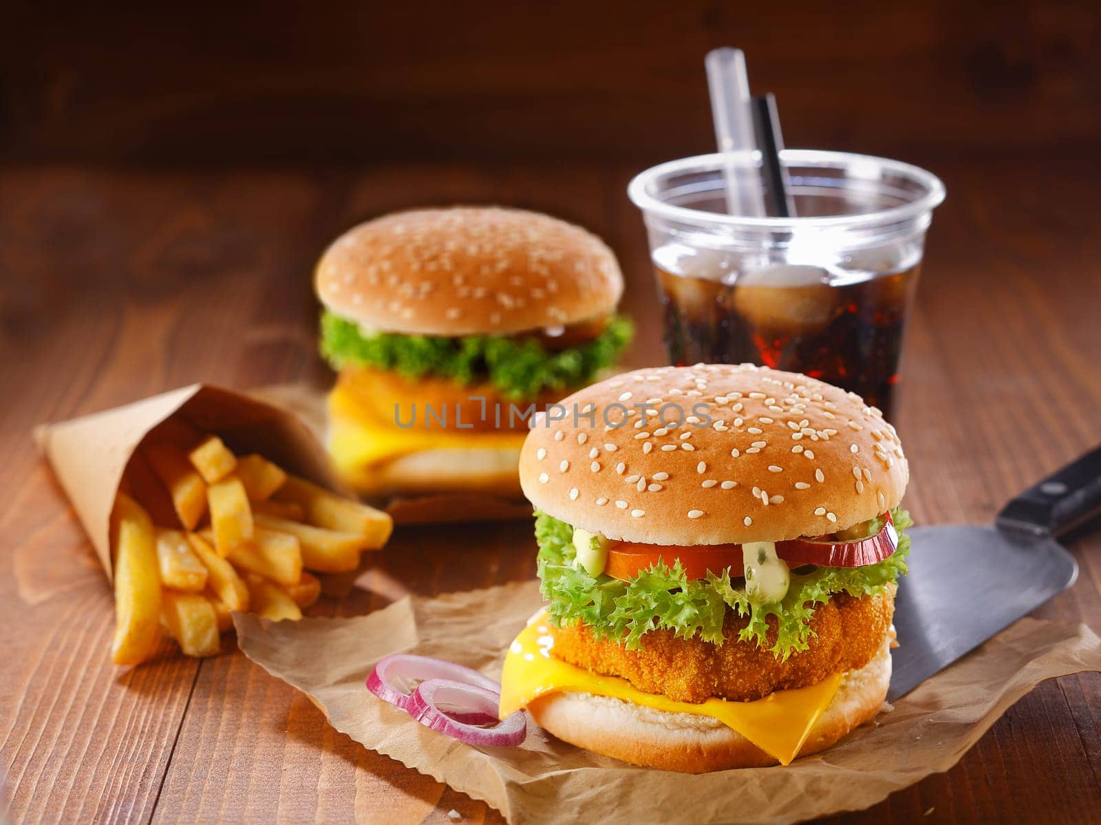 Fastfood meal made of two hamburgers, fried potatoes and soda with ice