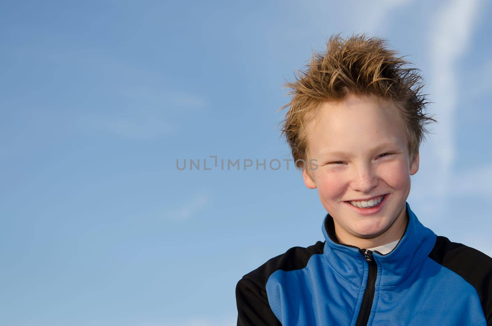 Happy teenager with spiky hair against blue sky background