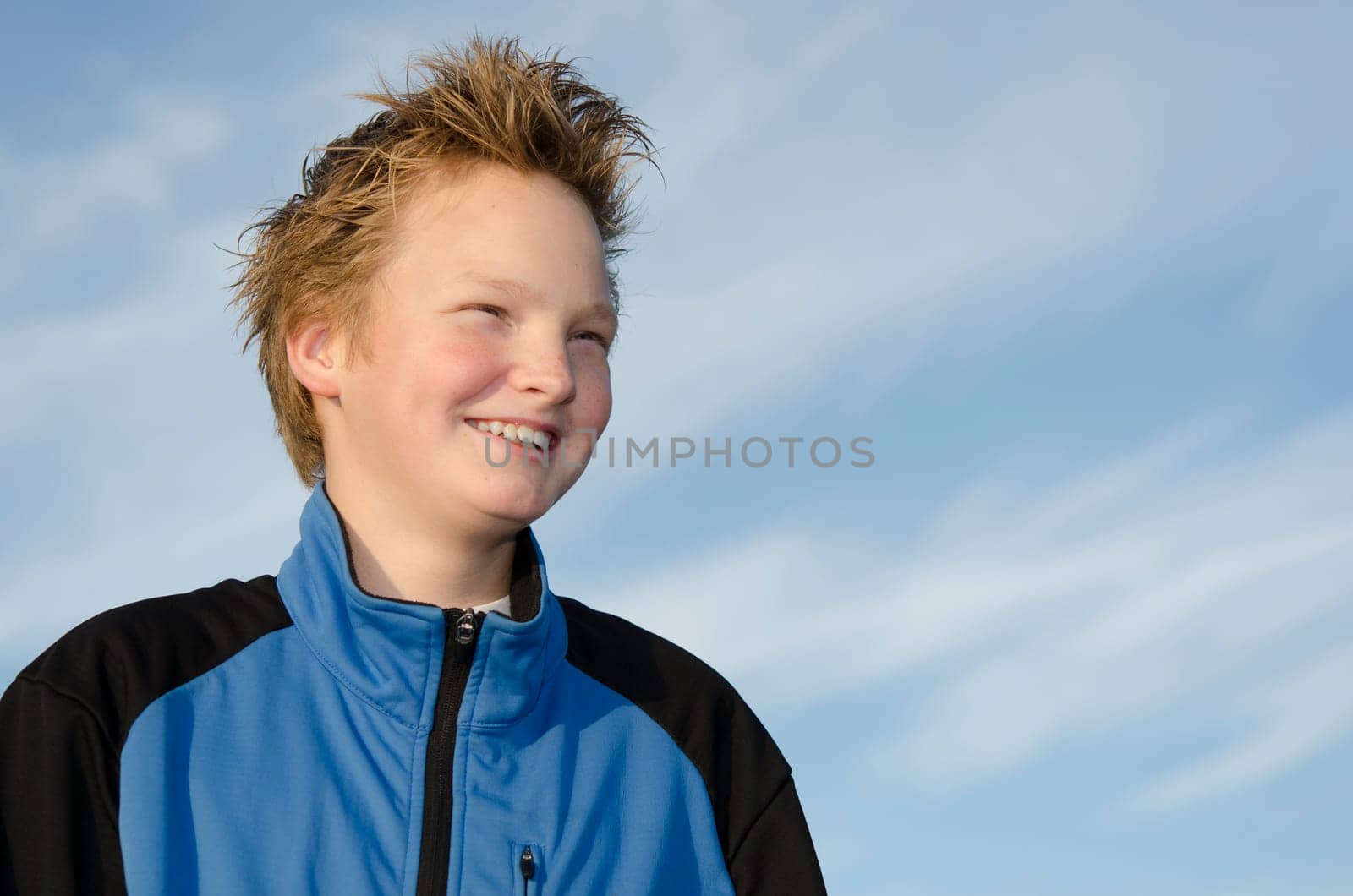 Portrait of laughing youngster against blue sky background