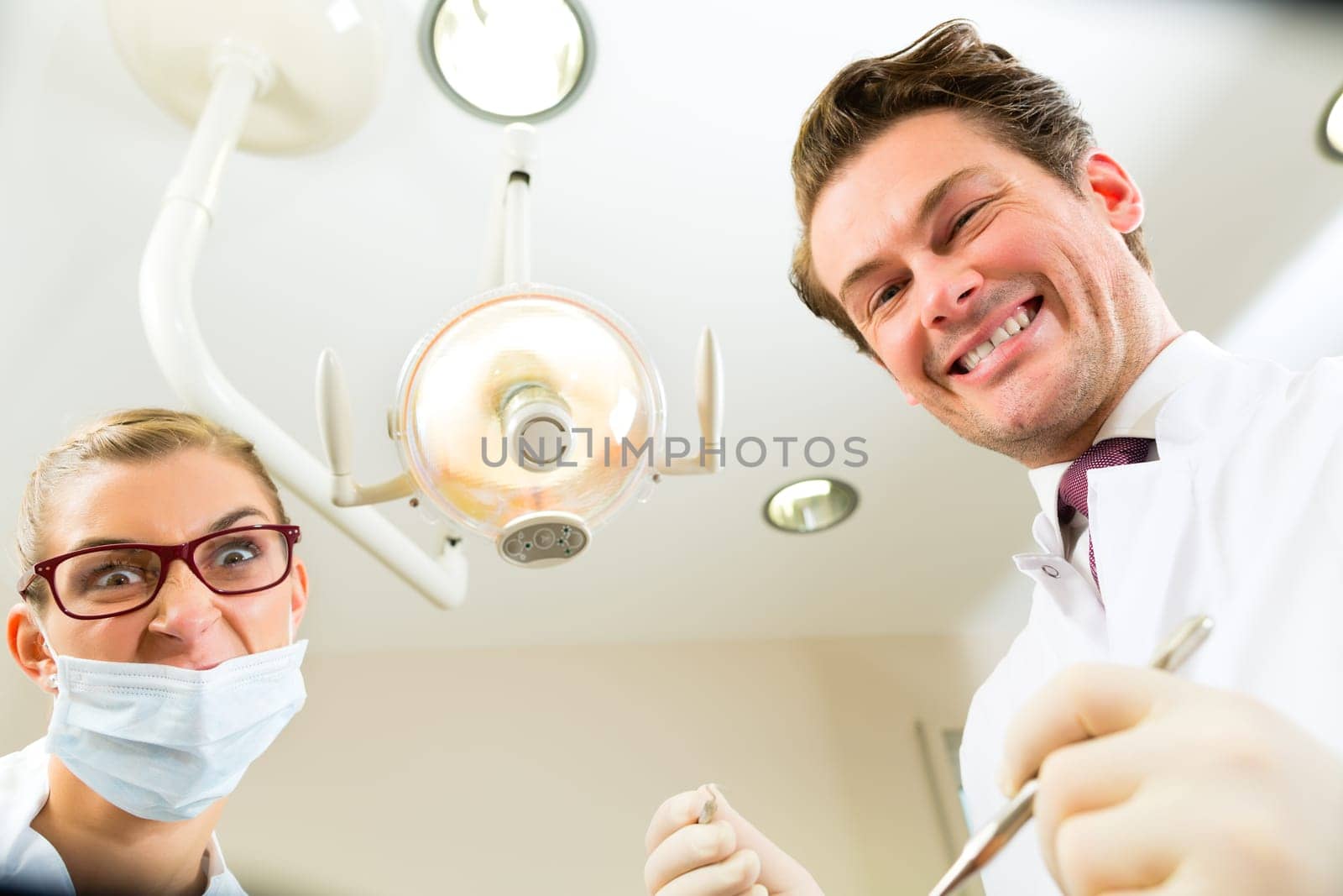 Scary dentist with dental assistant during a treatment from the patient's point of view