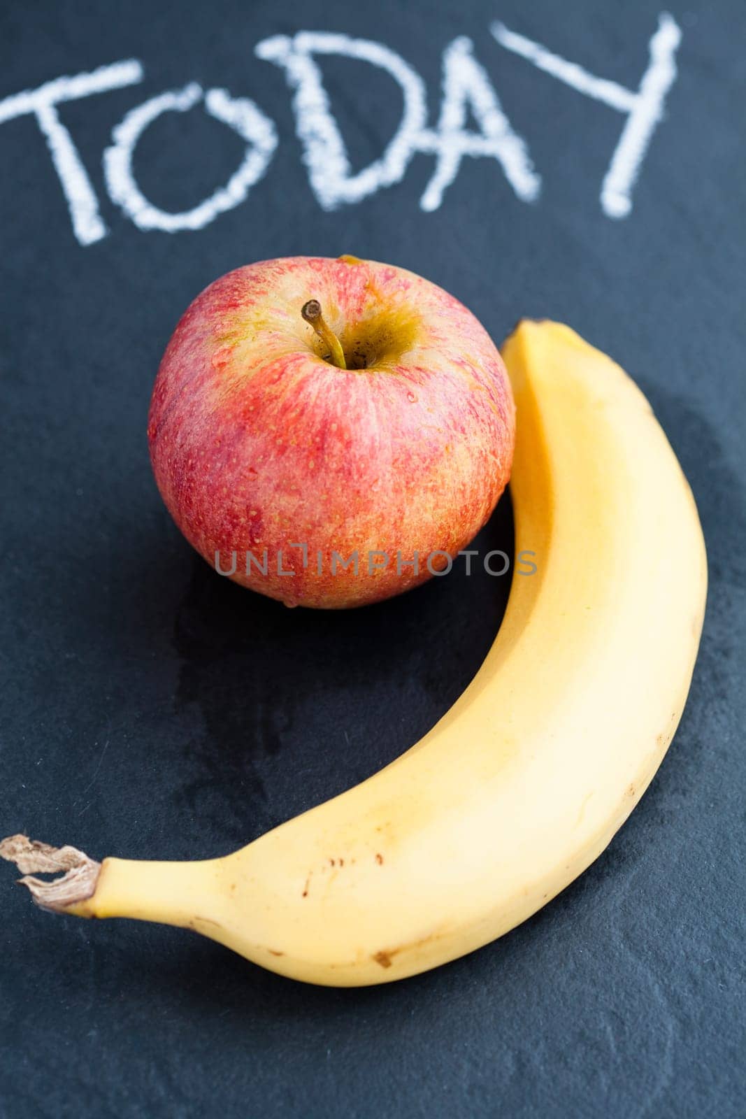 Apple and banana and word today written in chalk on dark background