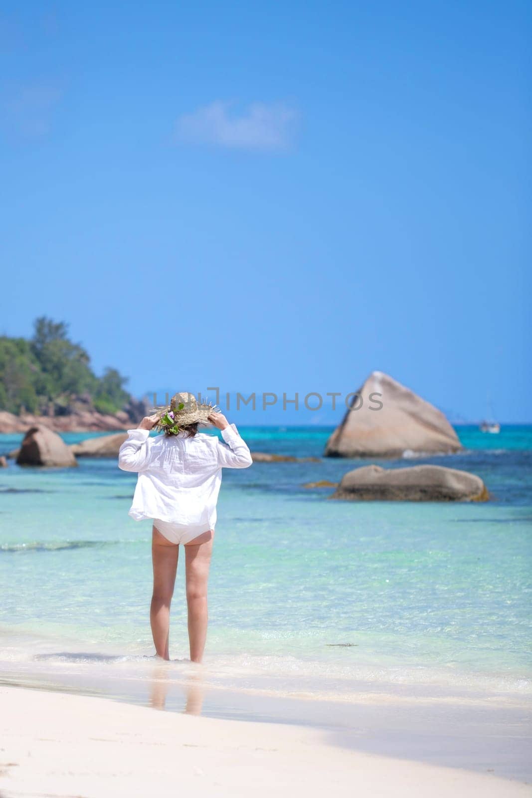 Young modern woman wearing a sun hat on the beach - Seychelles