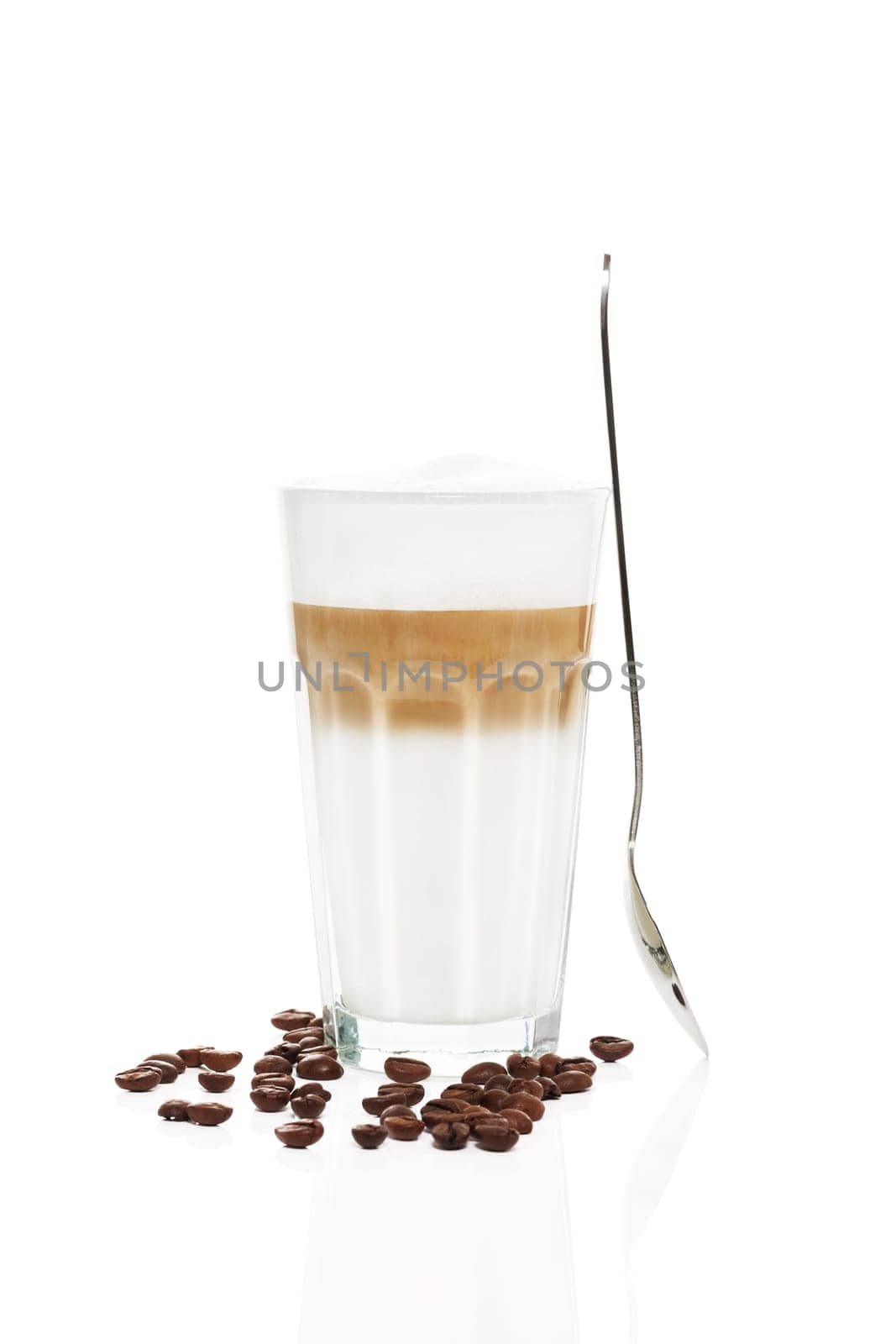 Latte macchiato with standing spoon and coffee beans on white background