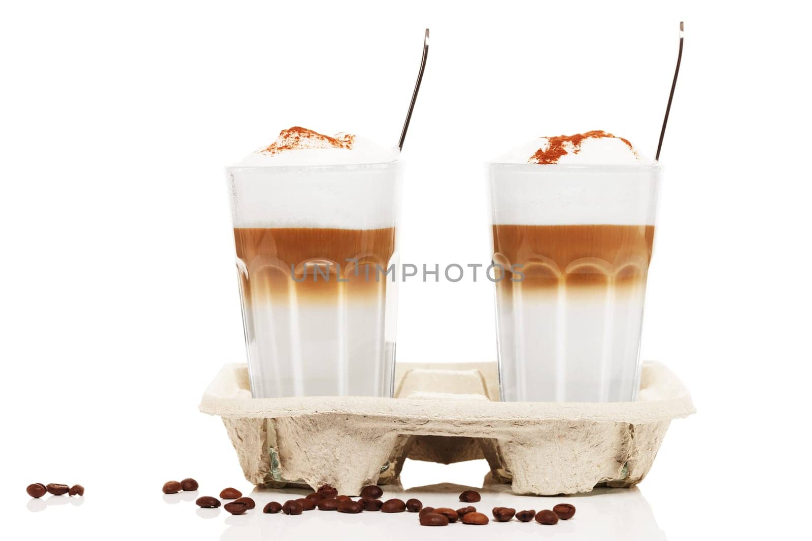 Latte macchiato to go with chocolate powder and coffee beans on white background