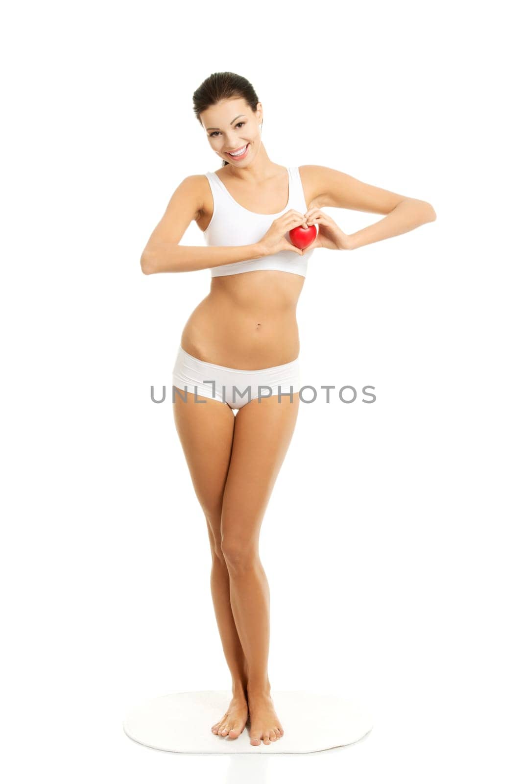 Happy Fit female in white sport underwear with red heart shaped toy