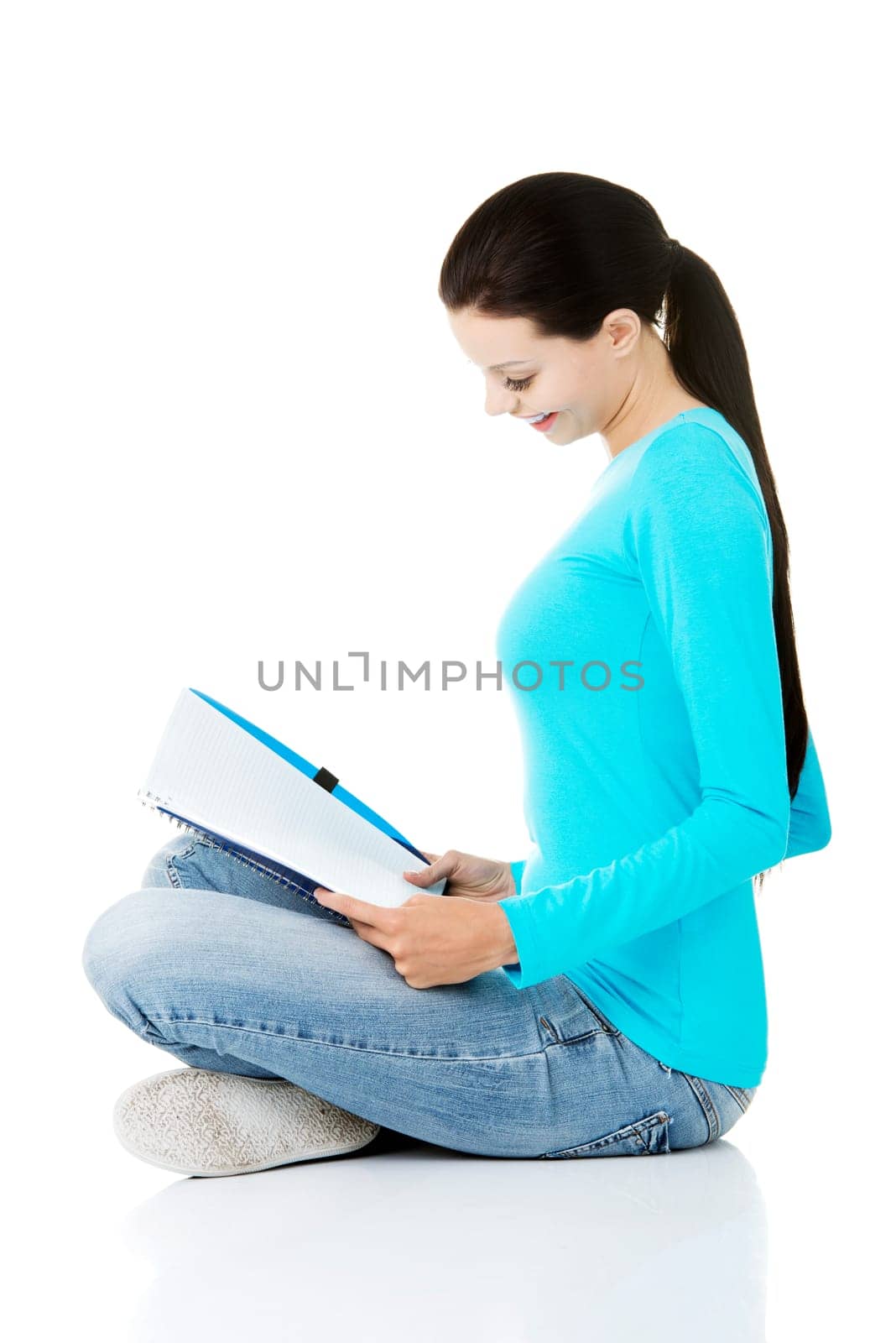 Happy student girl sitting on floor in casual clothes