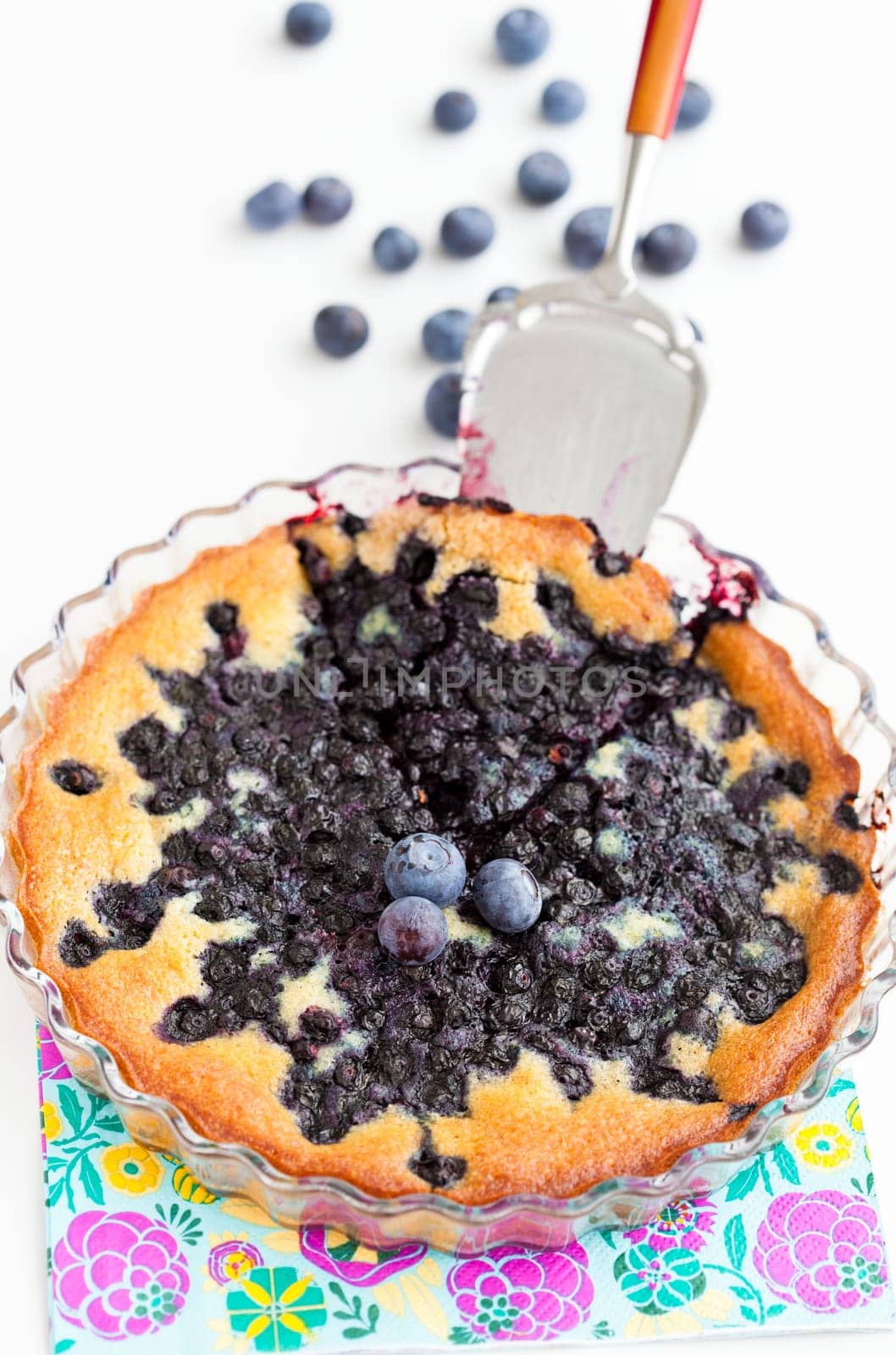 Closeup of delicious blueberry pie in glass dish with serving utensil