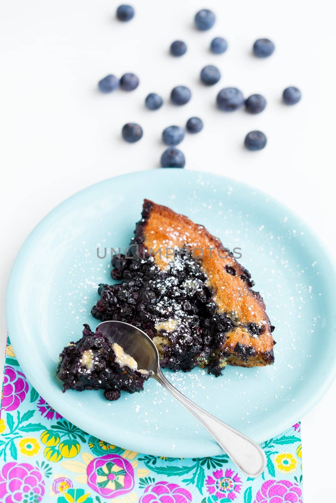 Closeup of slice of delicious blueberry pie on plate with spoon