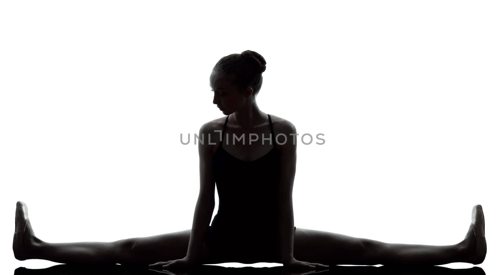 one caucasian young woman ballerina ballet dancer stretching warming up in silhouette studio on white background