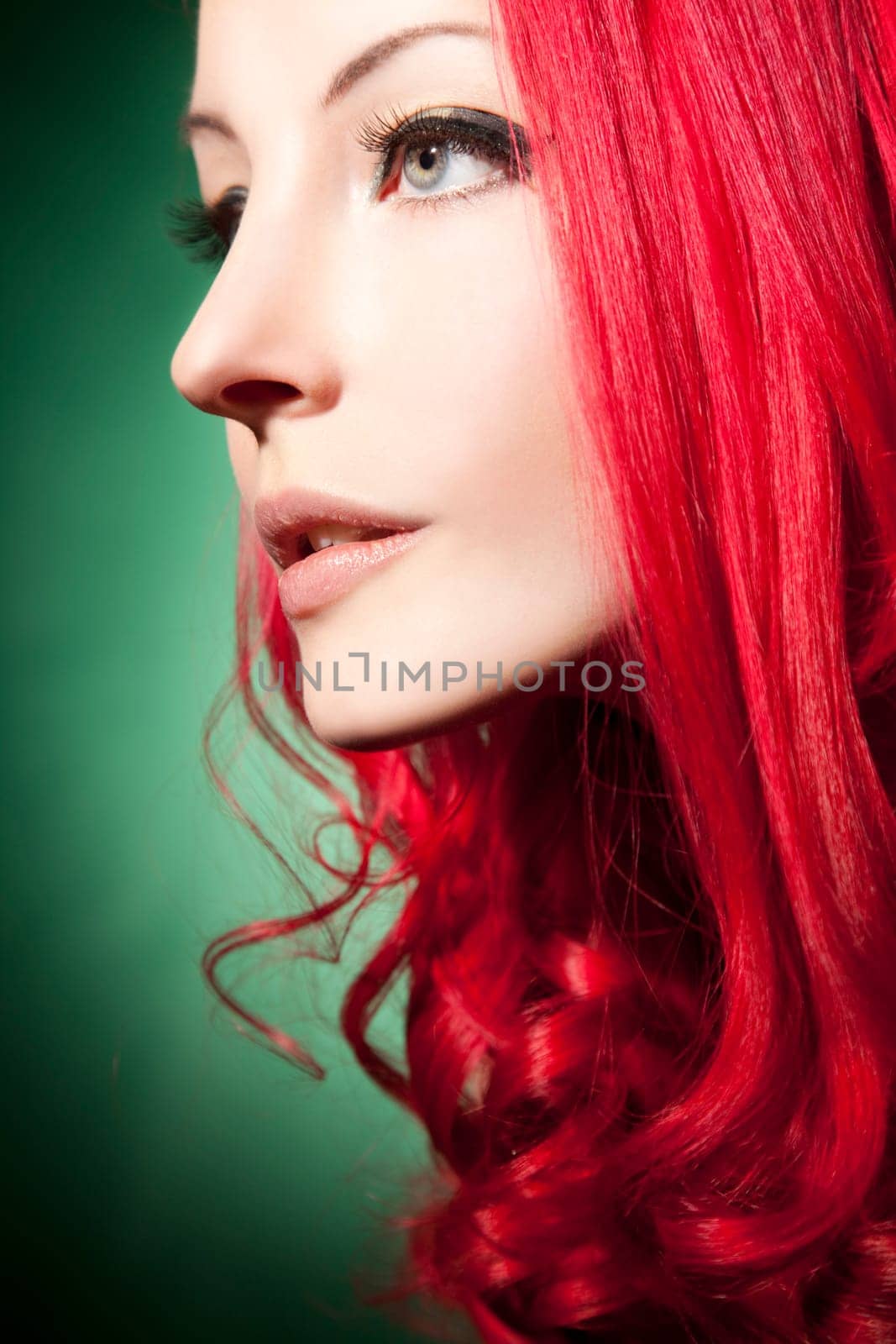 Beautiful young woman with red curls and perfect makeup
