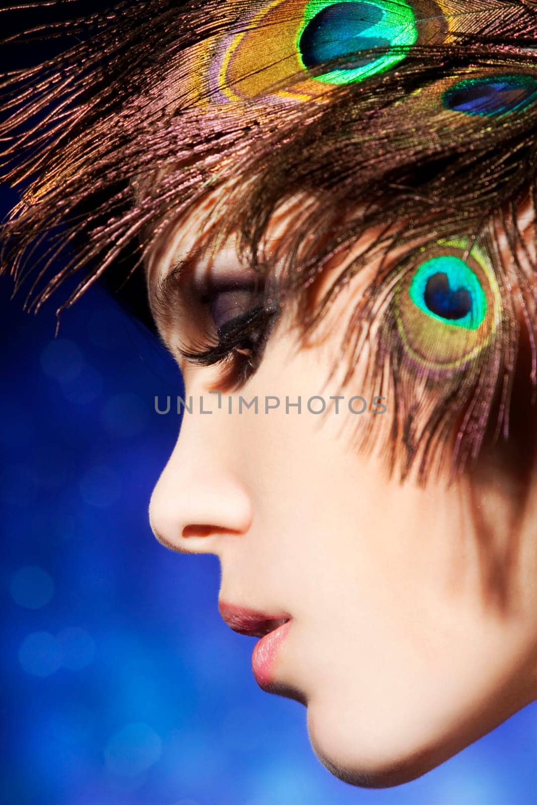 Beautiful young woman with perfect makeup and feather styling