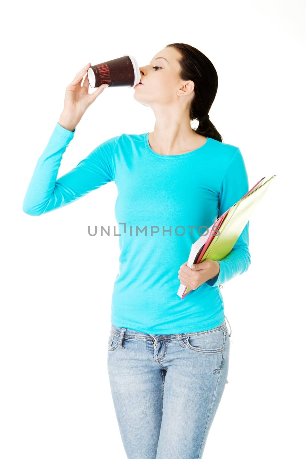 Young student or businesswoman with notebooks drinking coffee or tea from paper mug