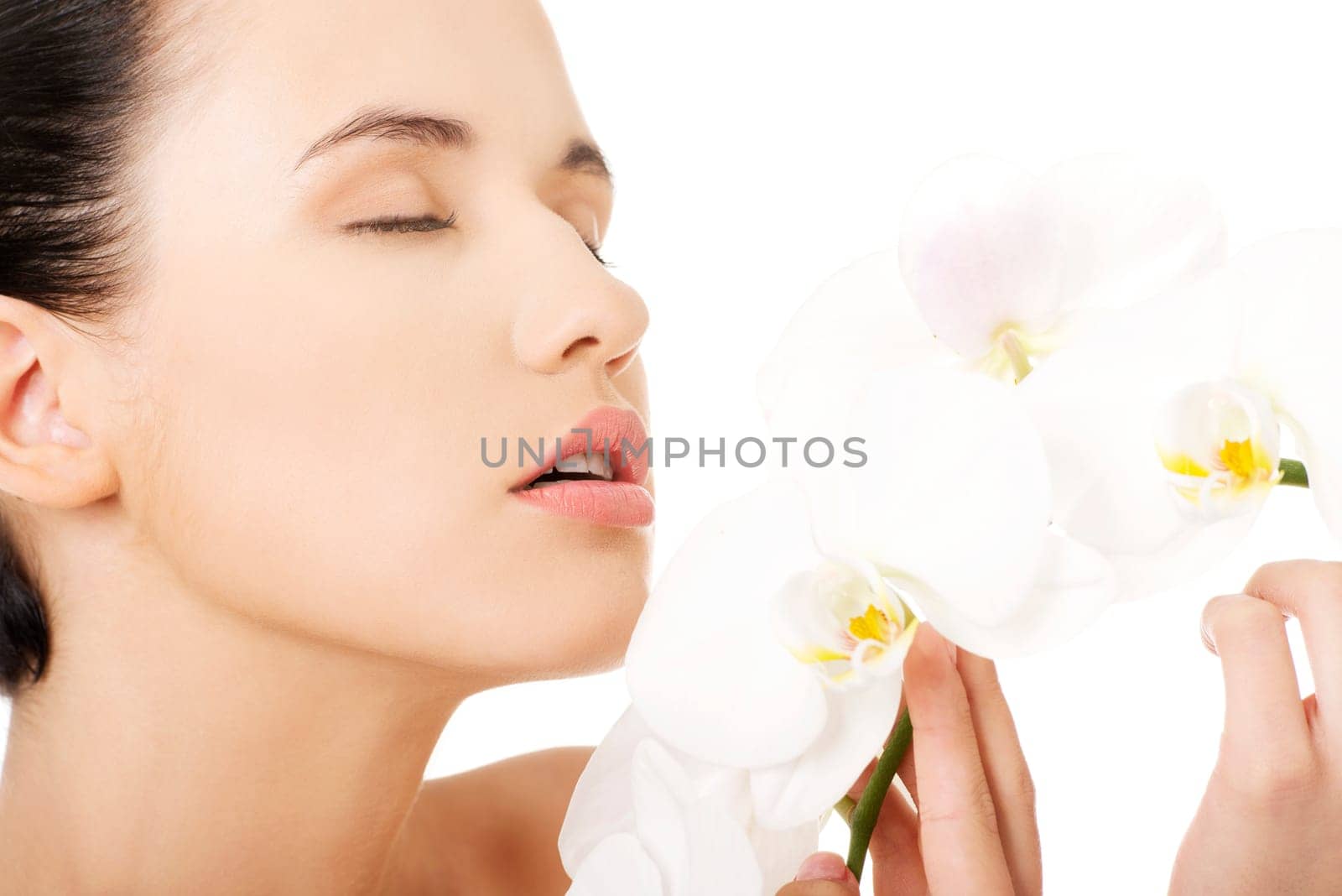 Portrait of beautiful young woman with health skin and with orchid flower. Spa concept.