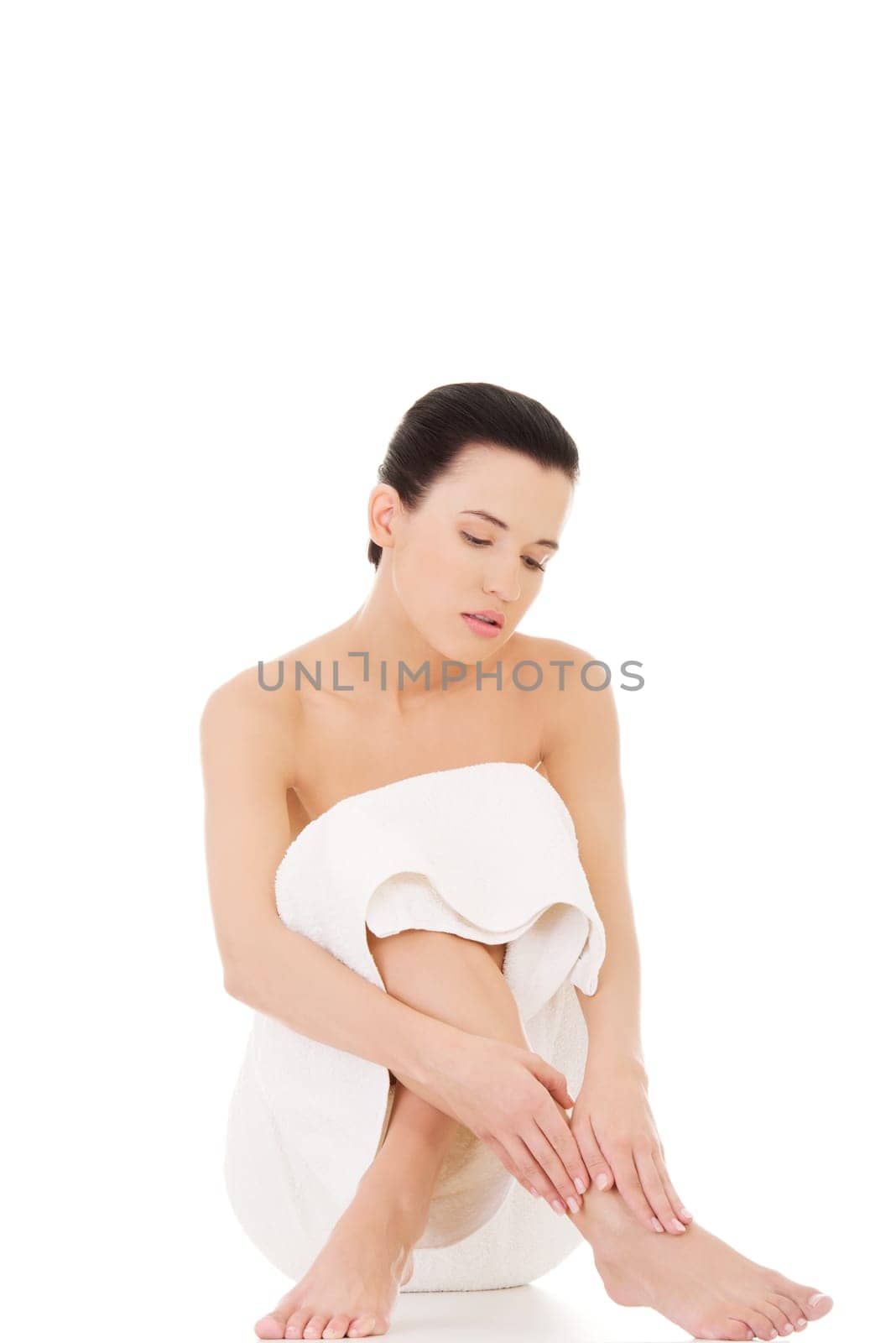 Naked woman covering her self with towel on white background.