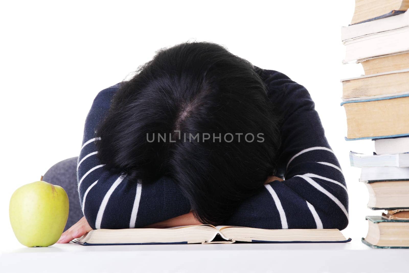 Young woman sleeping on desk next to pile of books, isolated on white