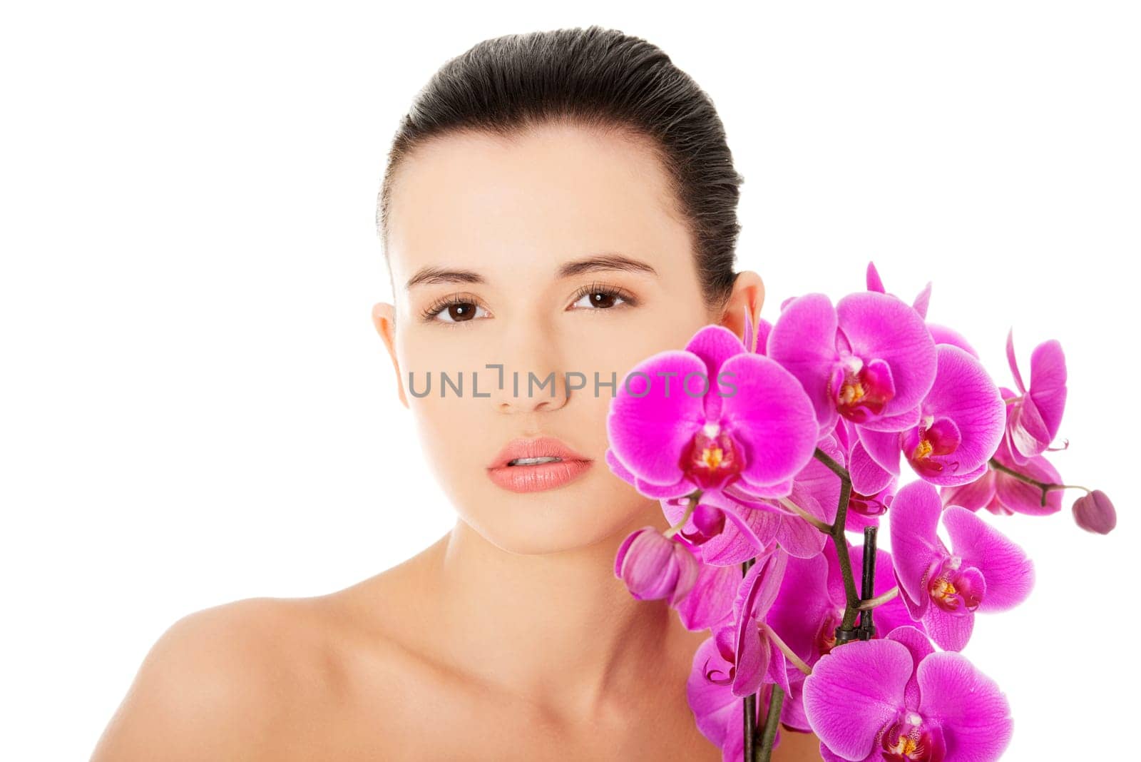 Portrait of beautiful young woman with health skin and with orchid flower. Spa concept.