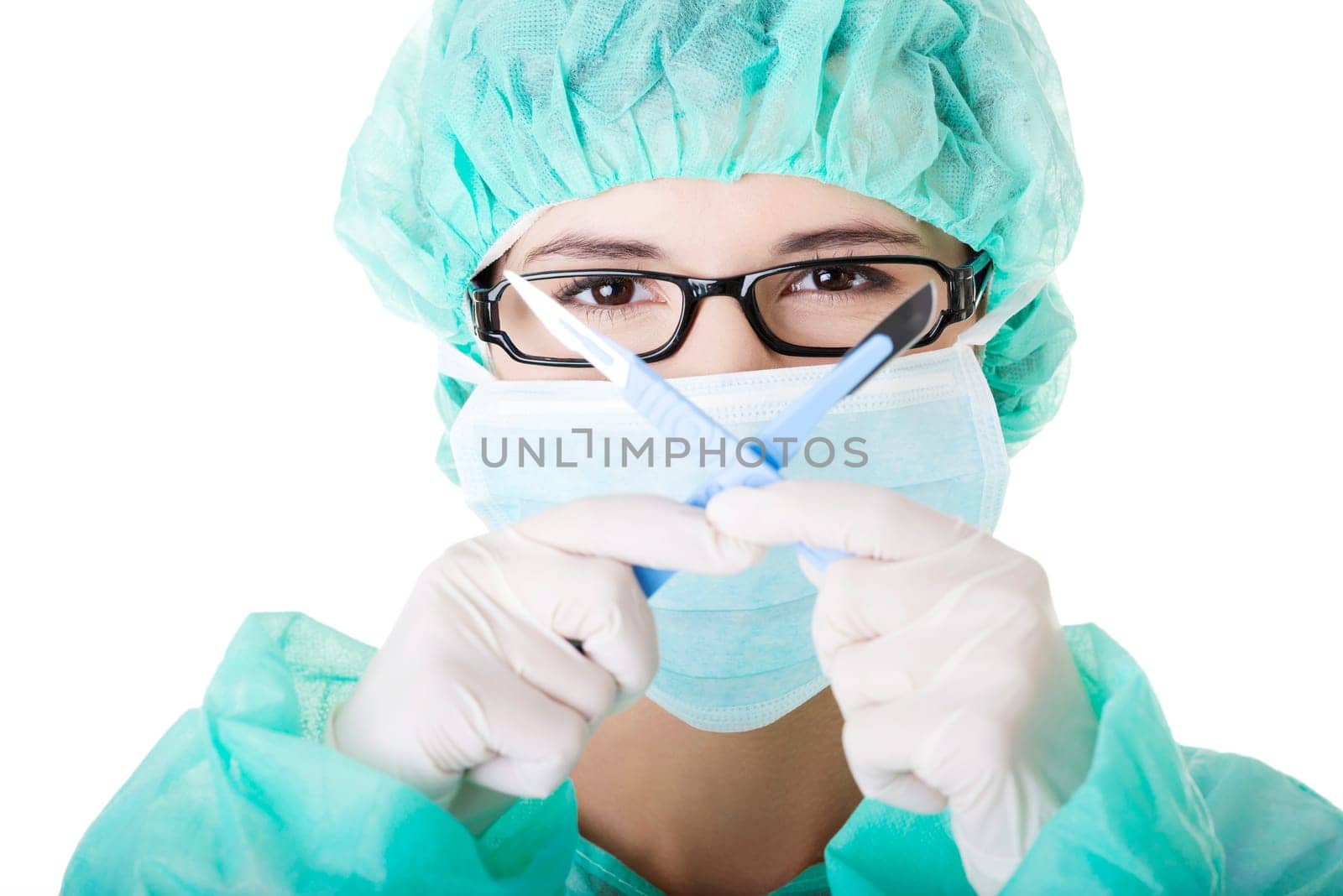 Portrait of woman doctor or nurse with surgical mask and cap holding scalpel