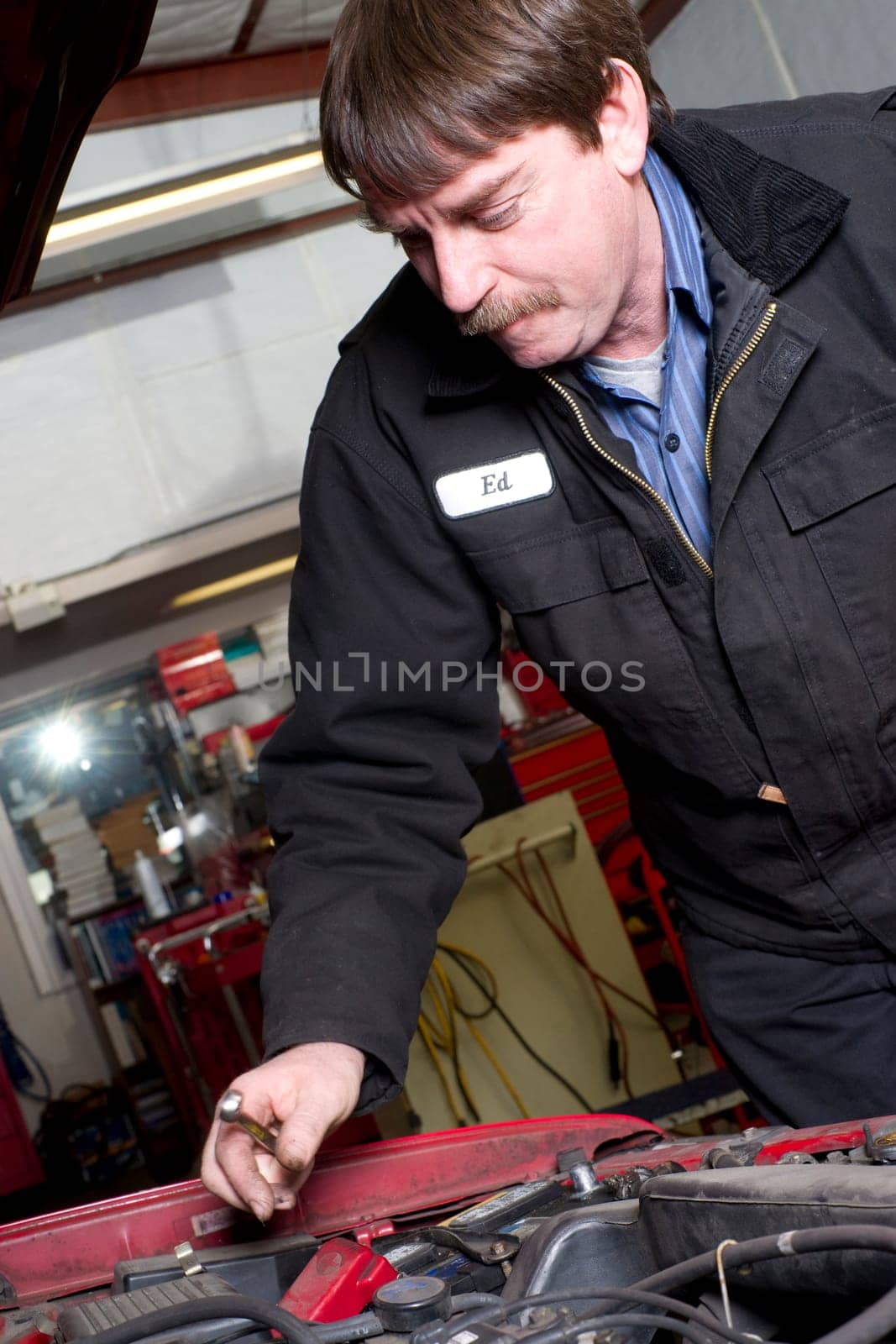 Professional Automotive Technician Works Under the Car Hood in Auto Repair