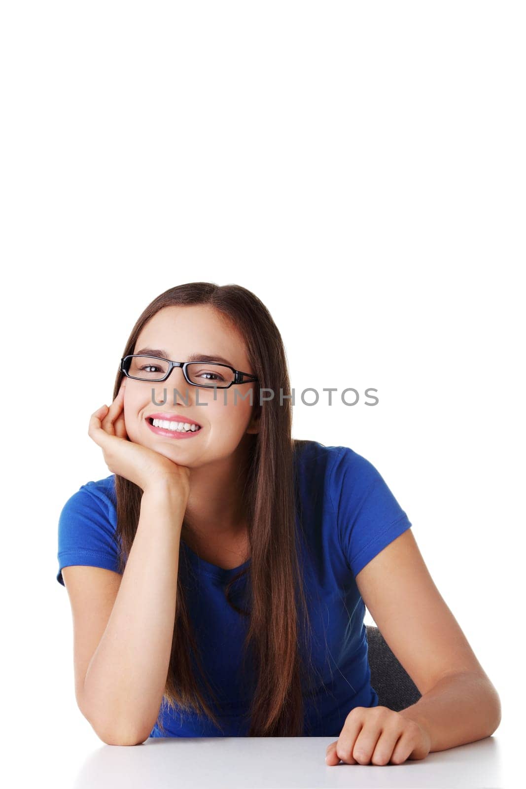 Smiling student girl sitting at the desk, isolated on white
