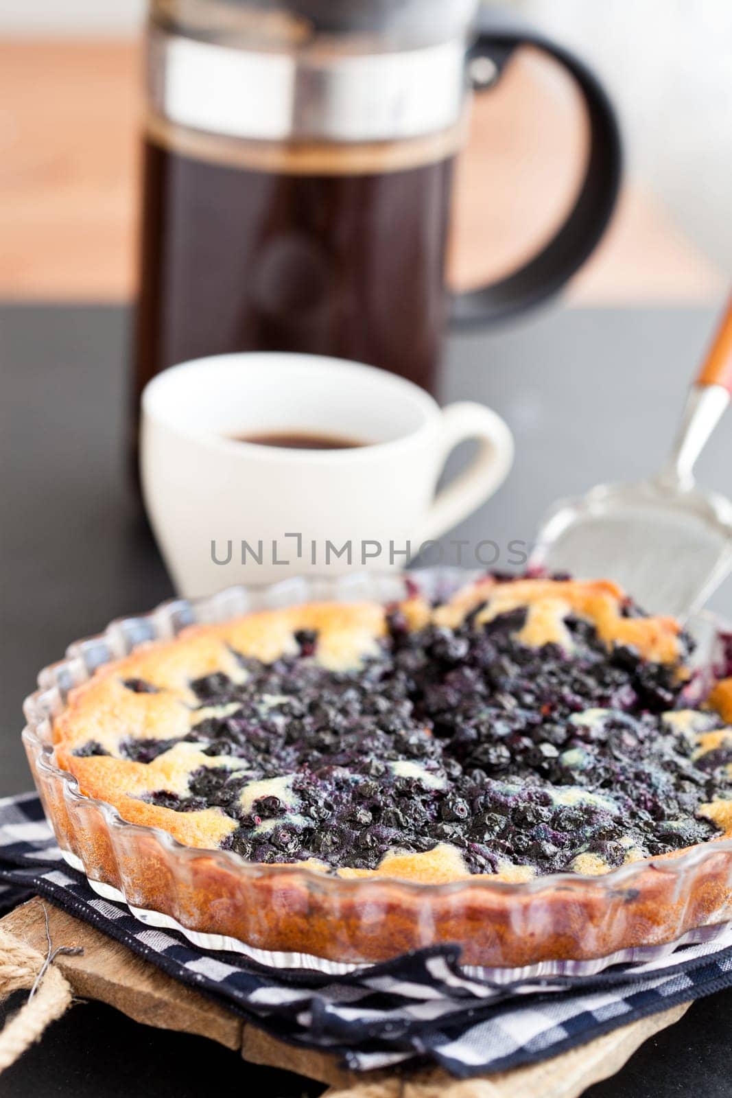 Blueberry pie in glass dish and server and coffee plunger and cup