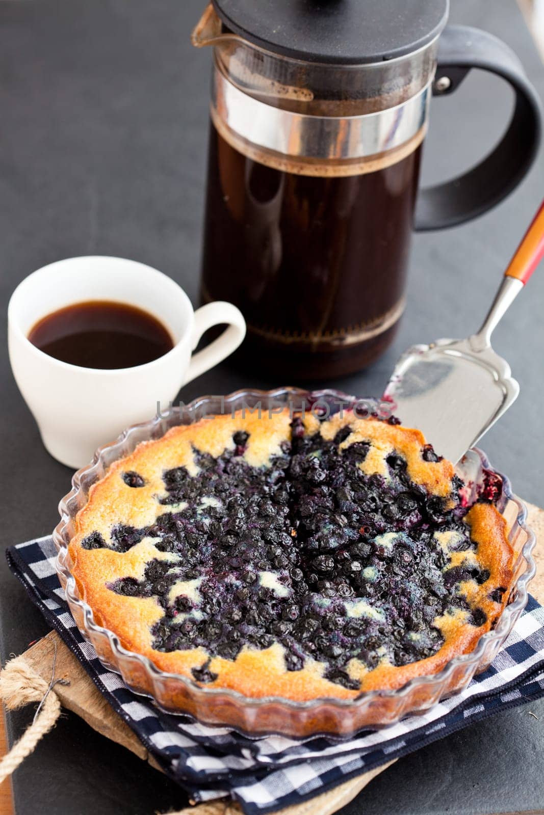 Blueberry pie in glass dish and server and coffee plunger and cup