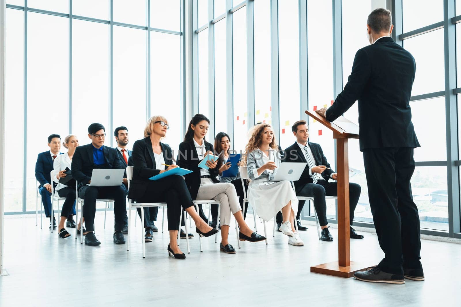 Group of business people meeting in a seminar conference . Audience listening to instructor in employee education training session . Office worker community summit forum with expert speaker . Jivy